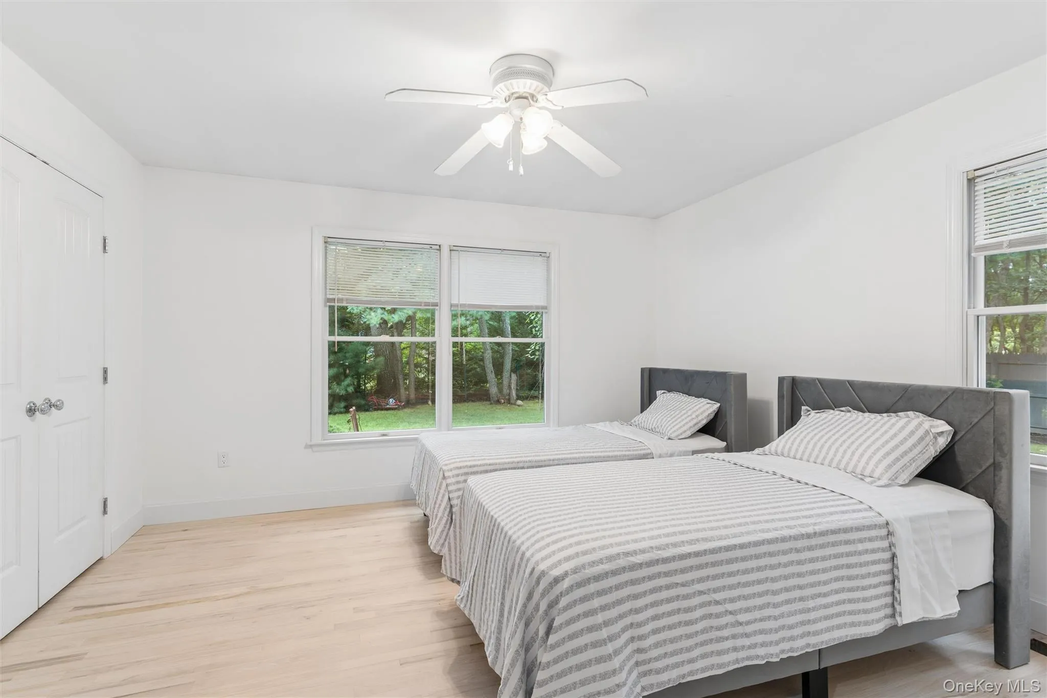White walls, light wood-finish flooring, and a ceiling fan White walls, light wood-finish flooring, and a ceiling fan