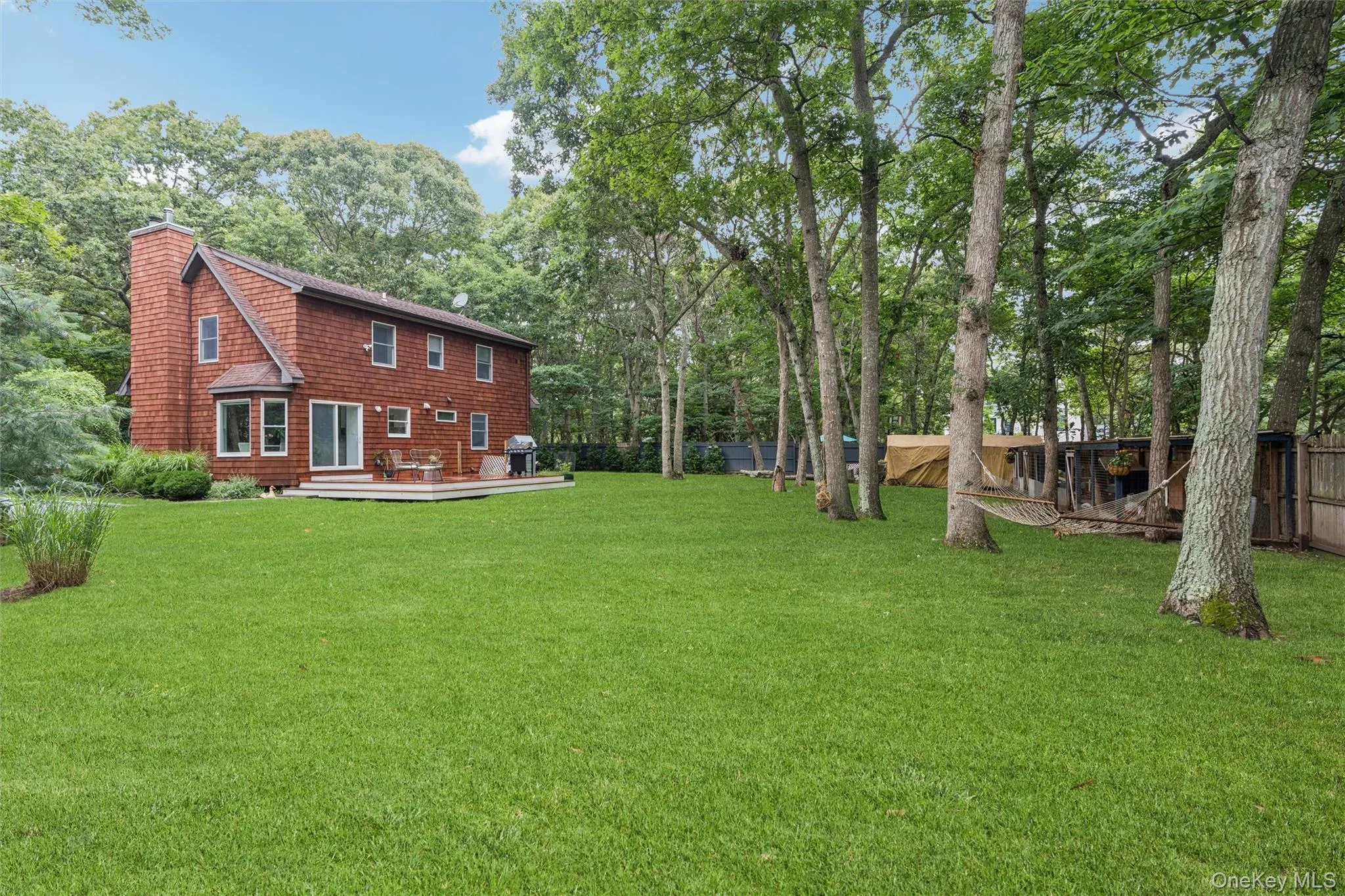 Wood-shingle exterior with a prominent brick chimney, multi-pane windows, and a rear deck Wood-shingle exterior with a prominent brick chimney, multi-pane windows, and a rear deck