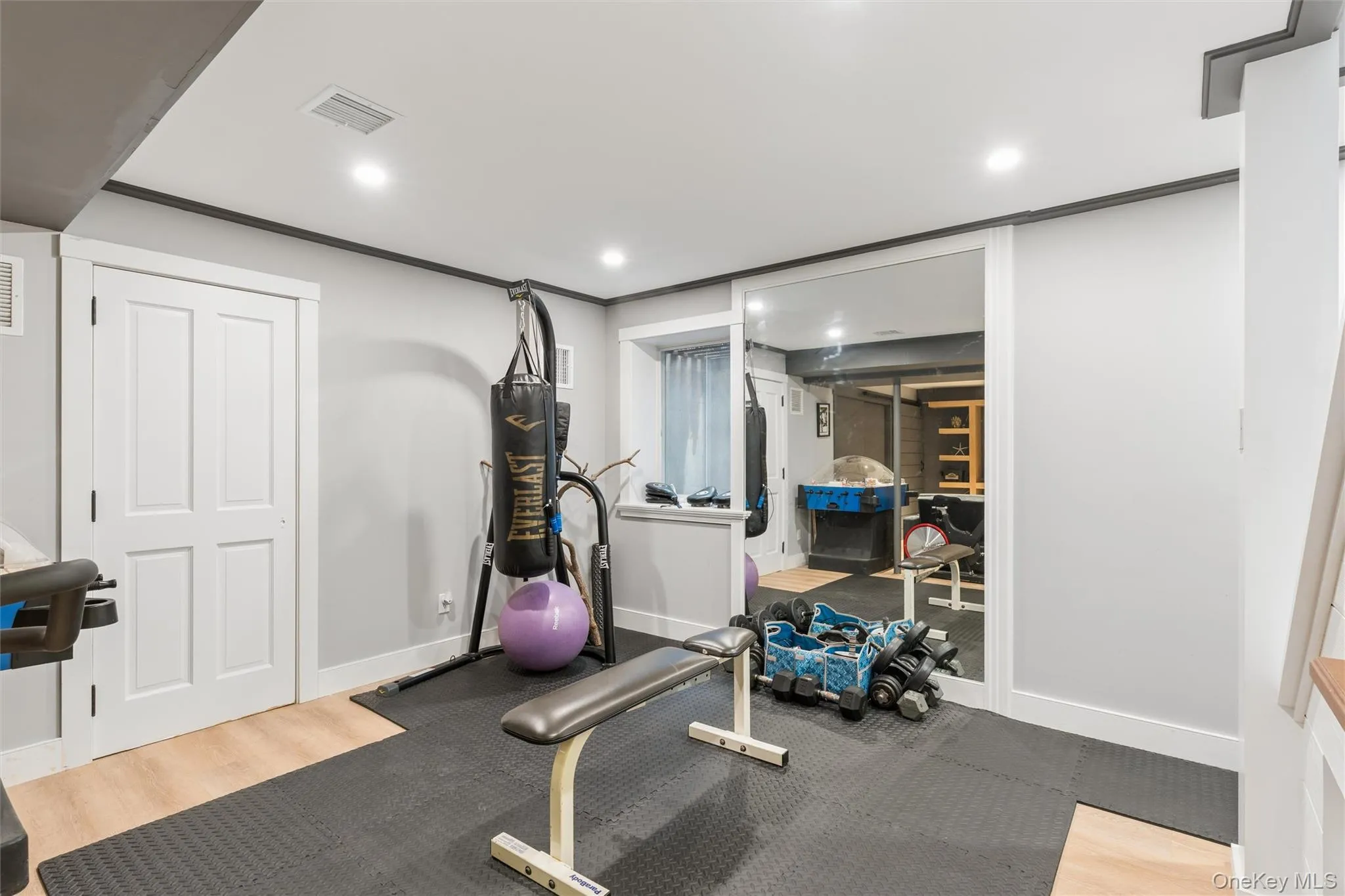 Recessed lighting, wood-finish flooring, white paneled door, mirrored wall, and a staircase with wood treads Recessed lighting, wood-finish flooring, white paneled door, mirrored wall, and a staircase with wood treads