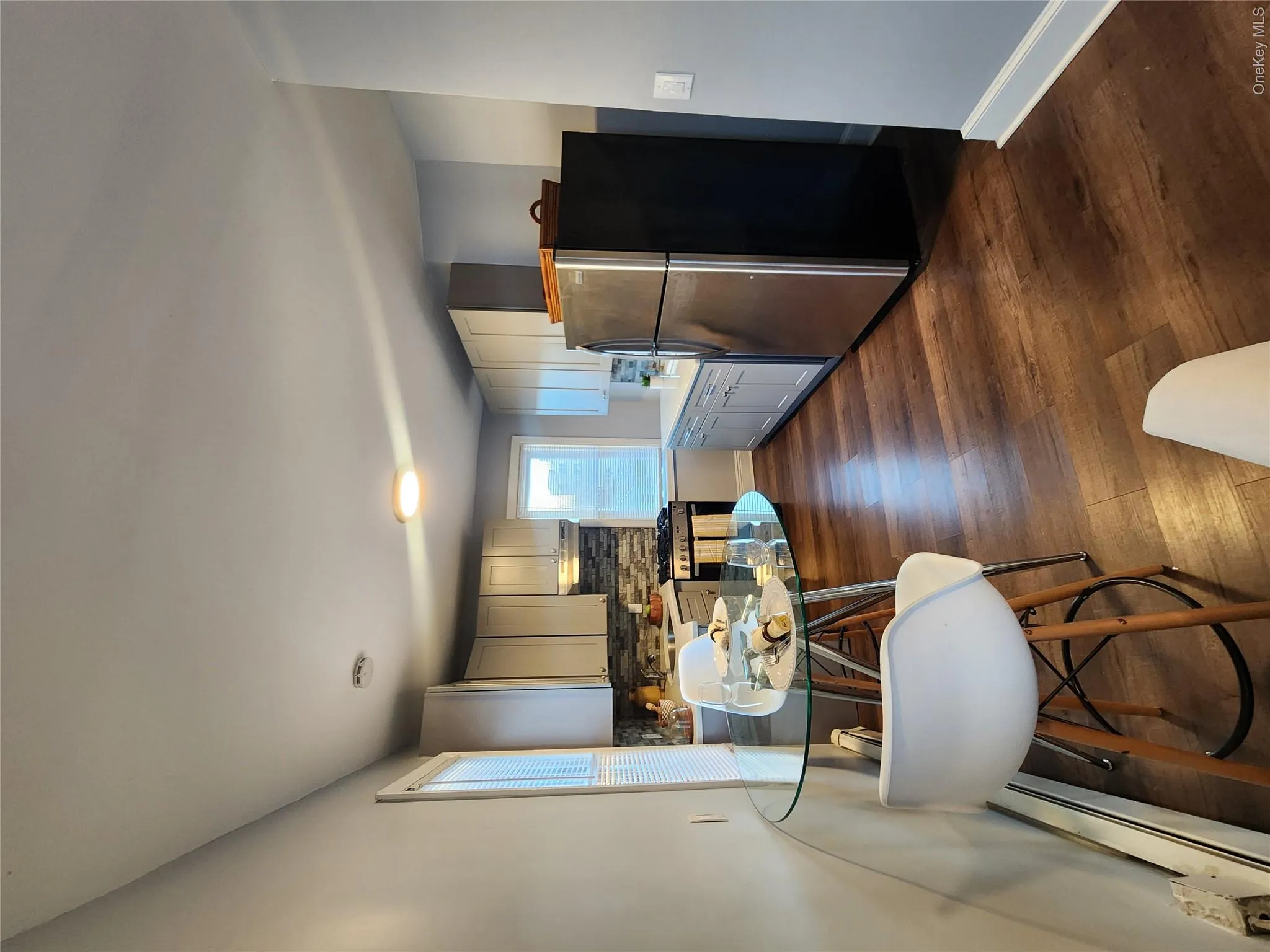 Kitchen with fridge, dark wood-style floors, a baseboard heating unit, tasteful backsplash, and stove Kitchen with fridge, dark wood-style floors, a baseboard heating unit, tasteful backsplash, and stove
