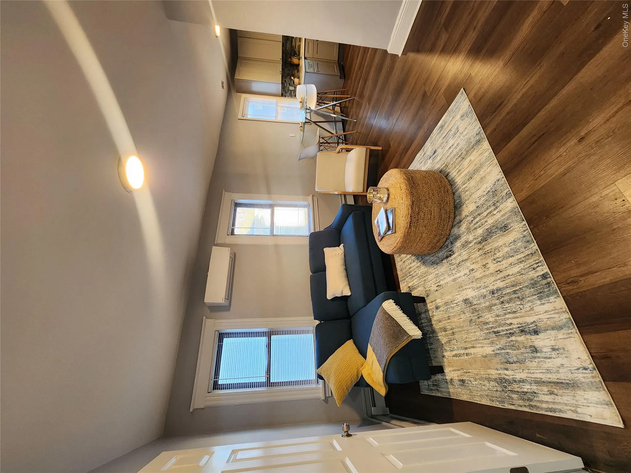 Living room with dark wood-type flooring, a wall mounted AC, and a baseboard heating unit Living room with dark wood-type flooring, a wall mounted AC, and a baseboard heating unit
