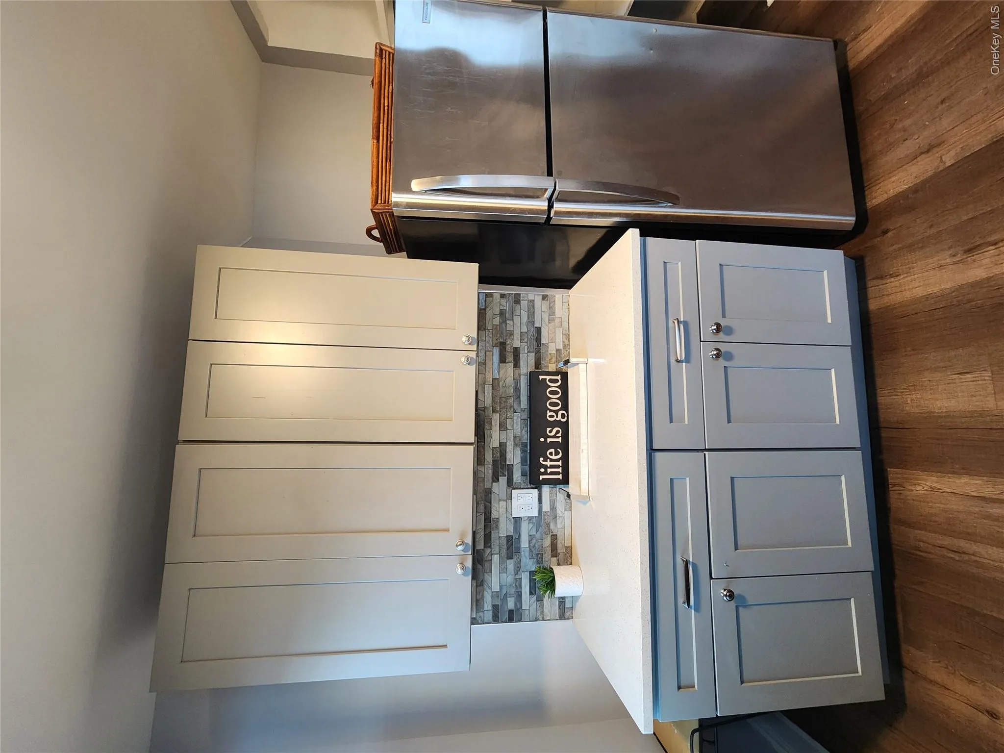 Kitchen with refrigerator, decorative backsplash, dark wood-style flooring, and light countertops Kitchen with refrigerator, decorative backsplash, dark wood-style flooring, and light countertops