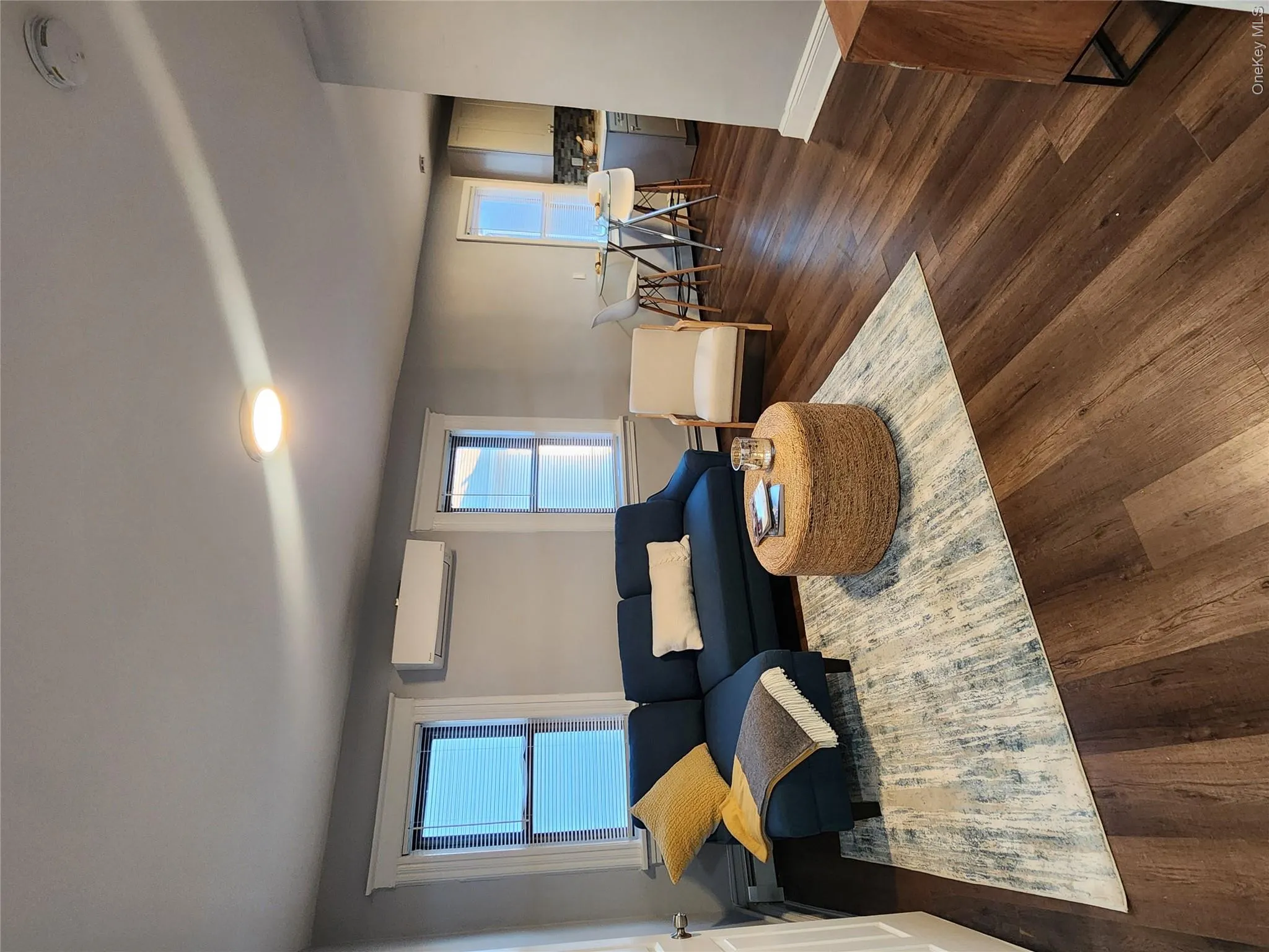 Living area with dark wood-style flooring, baseboard heating, and a wall mounted air conditioner Living area with dark wood-style flooring, baseboard heating, and a wall mounted air conditioner
