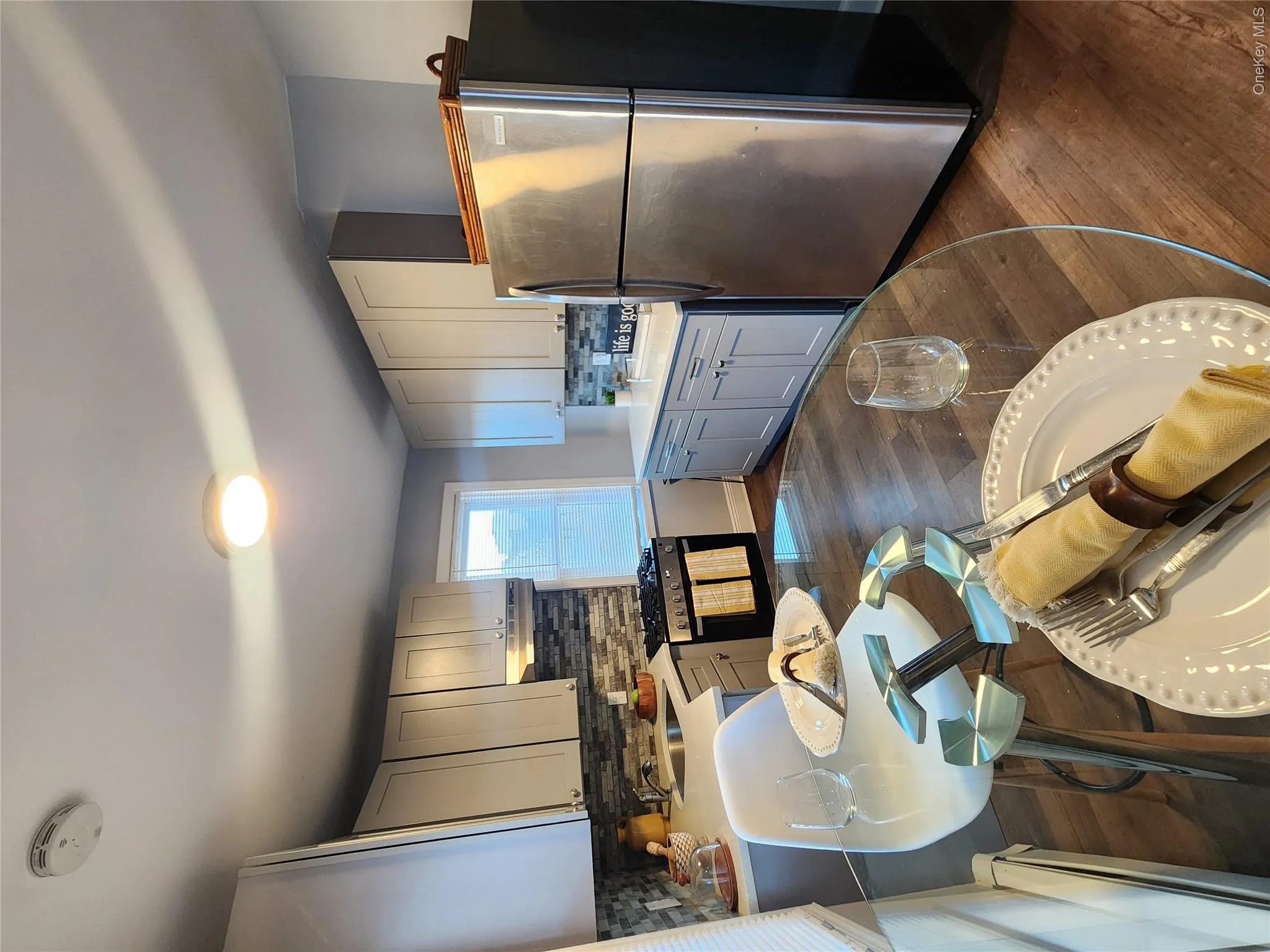 Kitchen with fridge, tasteful backsplash, a baseboard heating unit, dark wood finished floors, and light countertops Kitchen with fridge, tasteful backsplash, a baseboard heating unit, dark wood finished floors, and light countertops