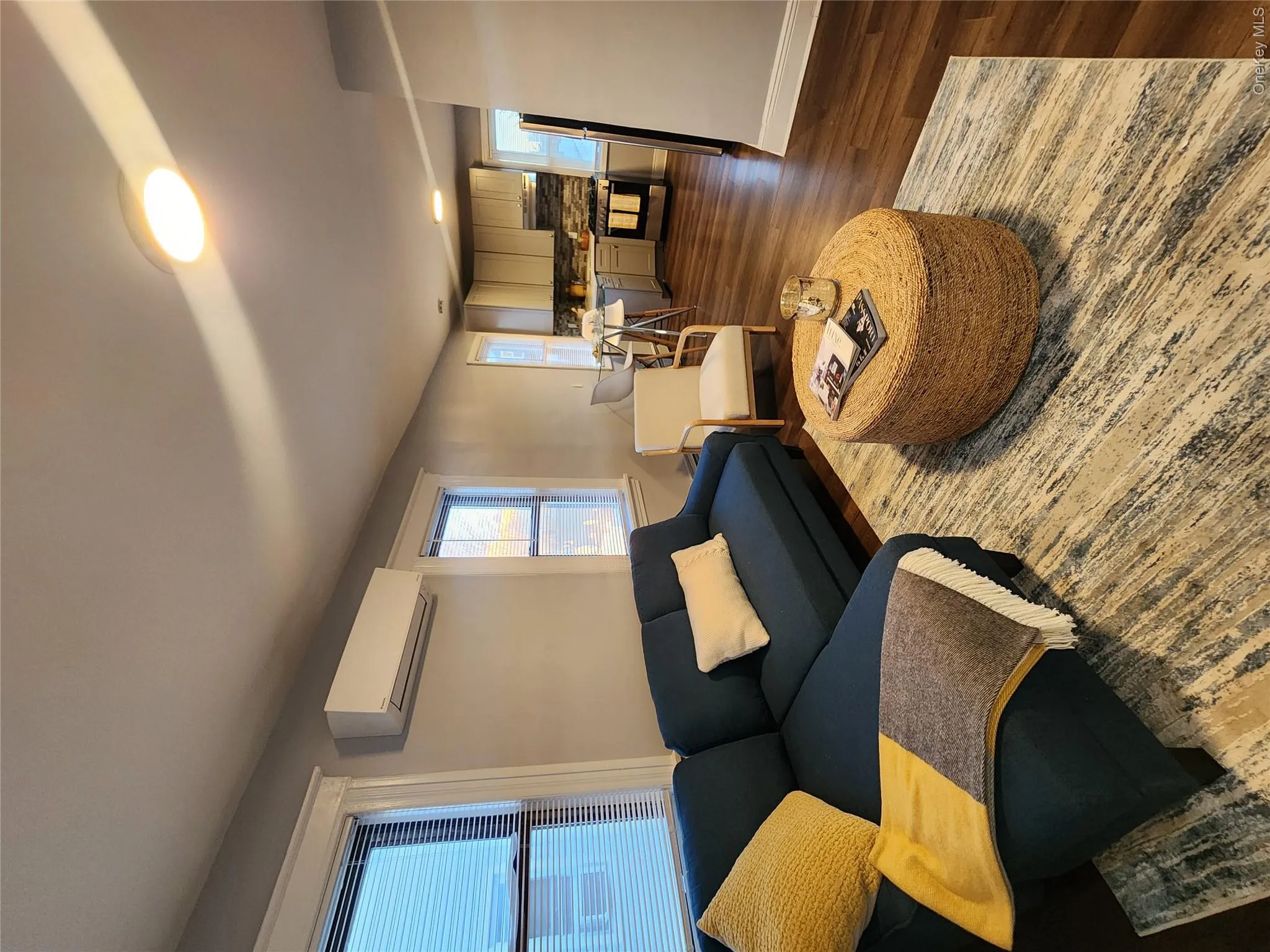 Living area with plenty of natural light, dark wood-type flooring, and an AC wall unit Living area with plenty of natural light, dark wood-type flooring, and an AC wall unit