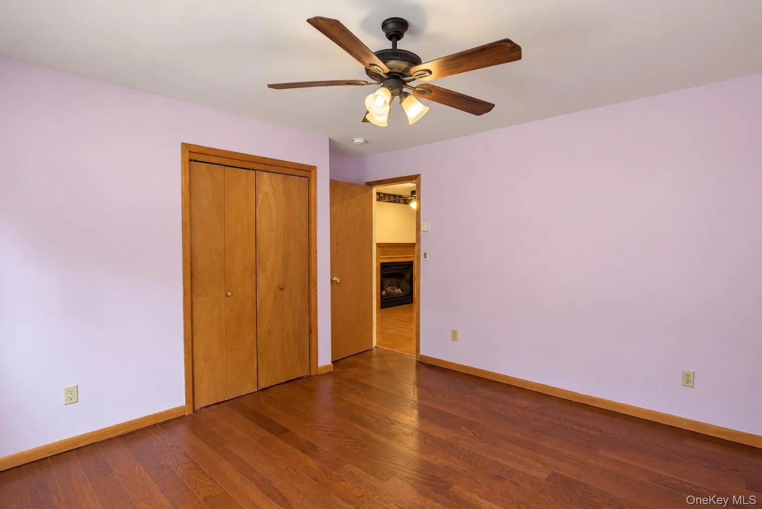 Wood-finish flooring, ceiling fan with integrated lighting, wood-paneled bi-fold closet, and recessed doorway Wood-finish flooring, ceiling fan with integrated lighting, wood-paneled bi-fold closet, and recessed doorway