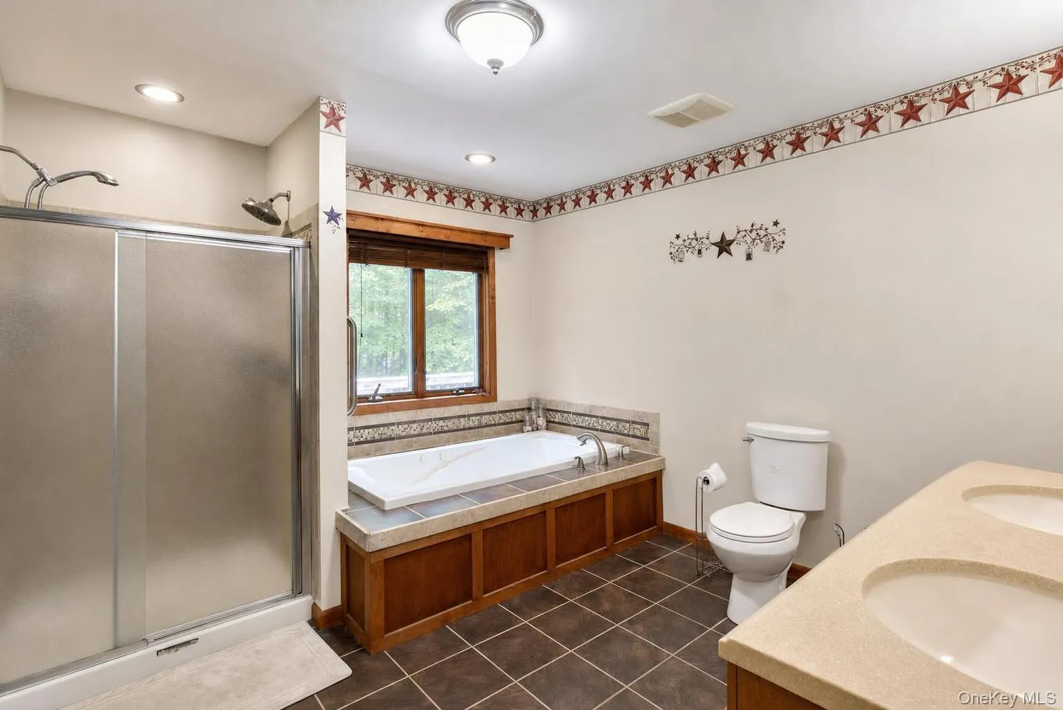 Dual vanity with integrated sinks, built-in Jacuzzi soaking tub, separate shower with frosted glass enclosure, and tiled flooring Dual vanity with integrated sinks, built-in Jacuzzi soaking tub, separate shower with frosted glass enclosure, and tiled flooring