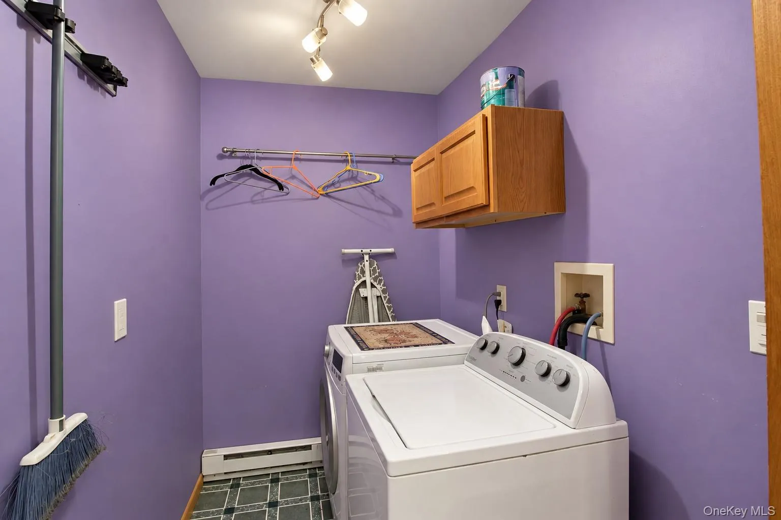 Laundry area with motion lighting, wall-mounted cabinetry, and a metal hanging rod Laundry area with motion lighting, wall-mounted cabinetry, and a metal hanging rod