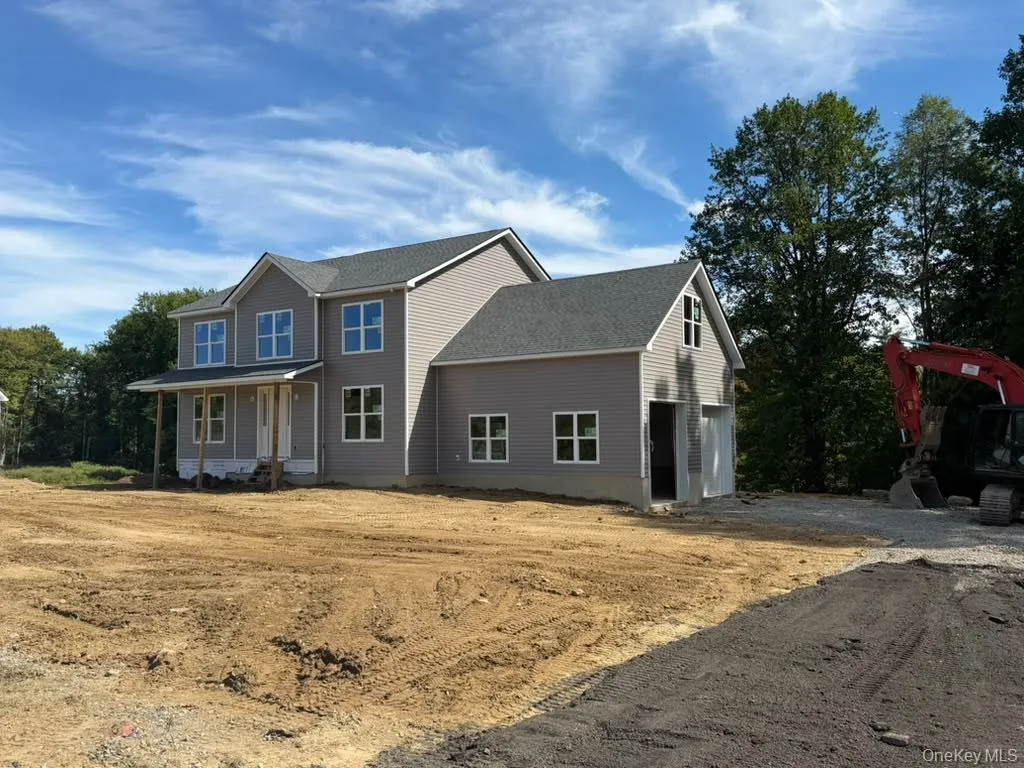 Two-story residence featuring light gray siding, white window frames, an attached two-car garage, a covered front porch, and a dark shingle roof Two-story residence featuring light gray siding, white window frames, an attached two-car garage, a covered front porch, and a dark shingle roof