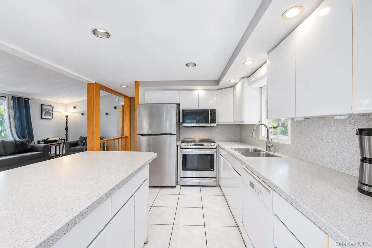 Kitchen featuring white cabinetry, light speckled countertops, stainless steel appliances, a double basin sink with a gooseneck faucet, and recessed lighting Kitchen featuring white cabinetry, light speckled countertops, stainless steel appliances, a double basin sink with a gooseneck faucet, and recessed lighting