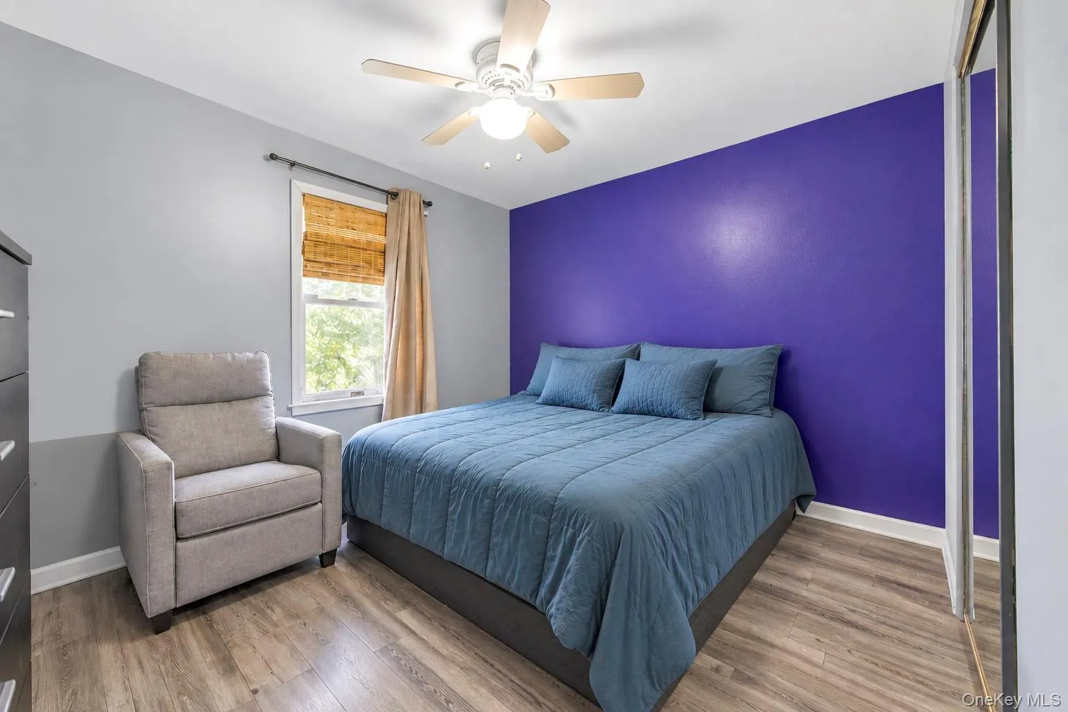 Wood-finish flooring with a multi-tone wall design, including a prominent purple accent wall Wood-finish flooring with a multi-tone wall design, including a prominent purple accent wall