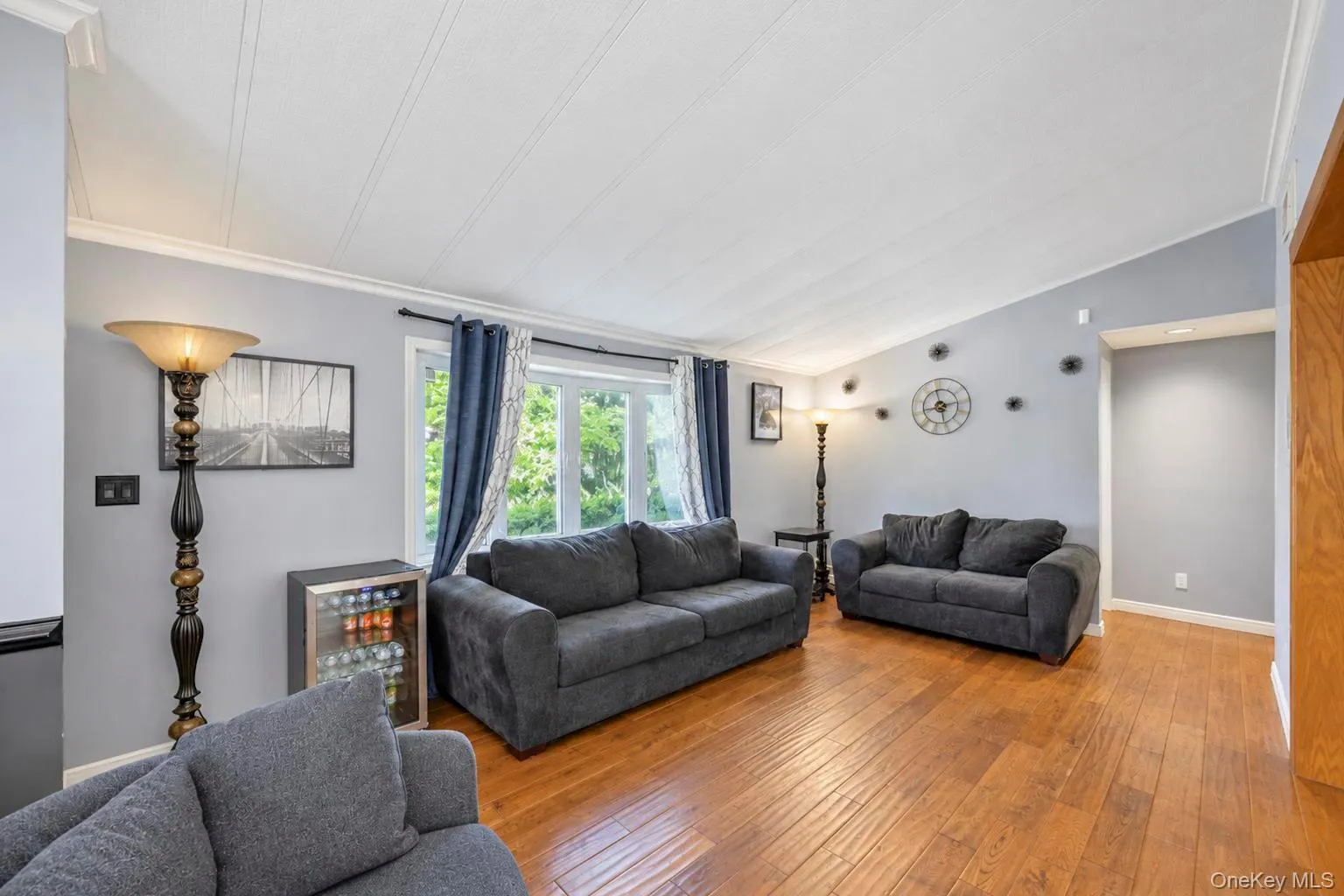 Vaulted ceiling with crown molding, wood-finish flooring, bay window, light gray wall paint Vaulted ceiling with crown molding, wood-finish flooring, bay window, light gray wall paint