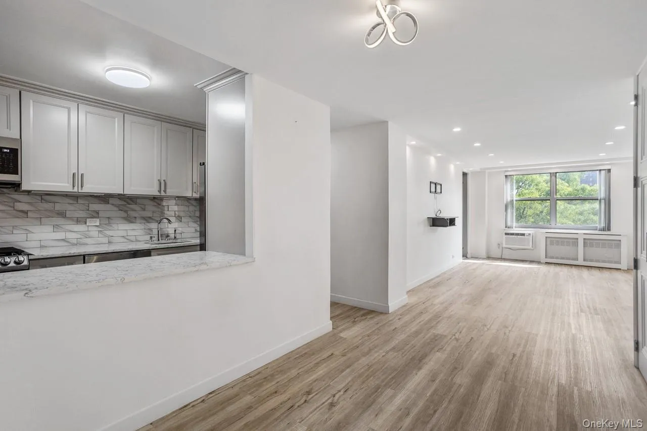 Kitchen featuring white shaker cabinetry, stainless steel appliances, and a marble-patterned backsplash Kitchen featuring white shaker cabinetry, stainless steel appliances, and a marble-patterned backsplash