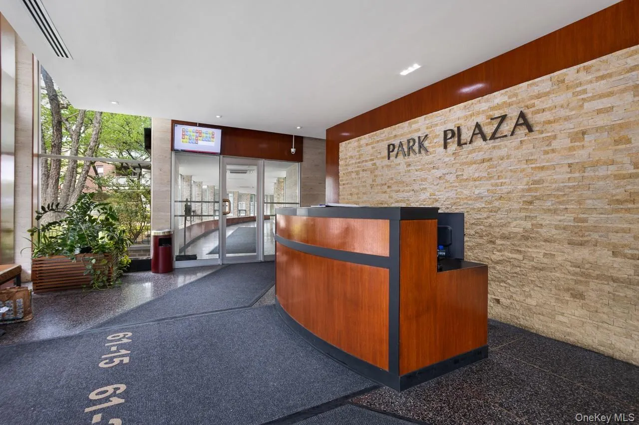 Reception area featuring a wood-finish desk with a dark countertop, a stone-finish accent wall, and large glass windows Reception area featuring a wood-finish desk with a dark countertop, a stone-finish accent wall, and large glass windows