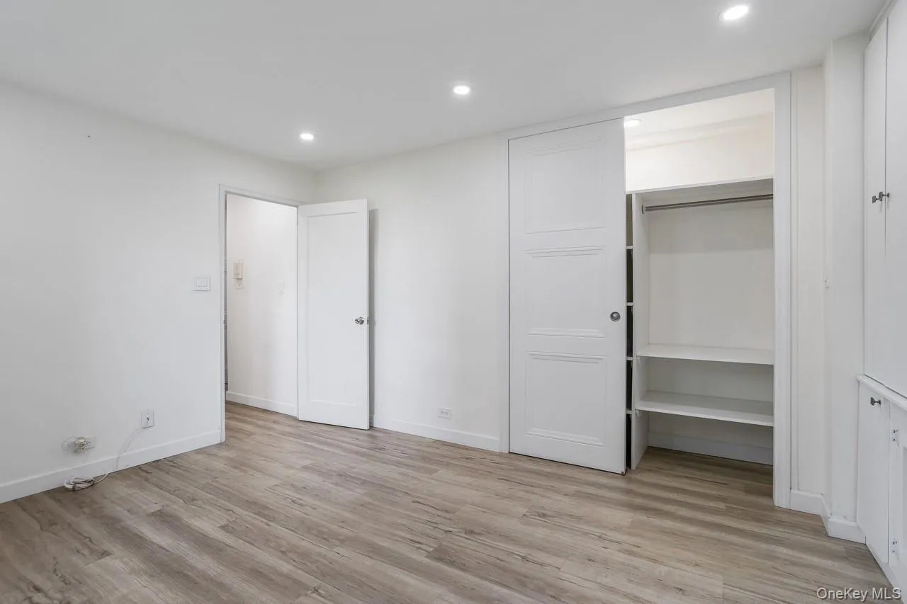 Recessed lighting, wood-finish flooring, white walls, built-in shelving, and a sliding closet door Recessed lighting, wood-finish flooring, white walls, built-in shelving, and a sliding closet door