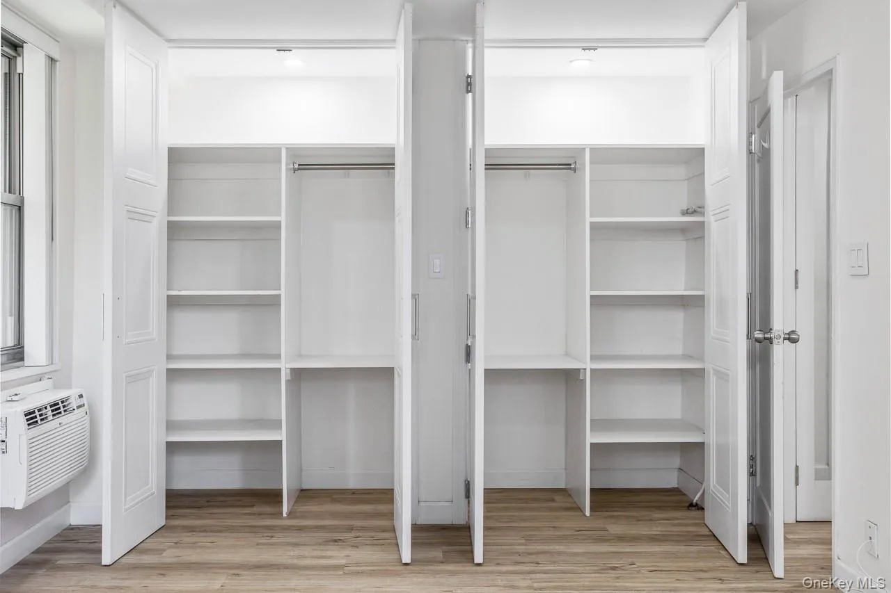 Dual closet system featuring white bi-fold doors, integrated shelving, and hanging rods, set against wood-finish flooring Dual closet system featuring white bi-fold doors, integrated shelving, and hanging rods, set against wood-finish flooring