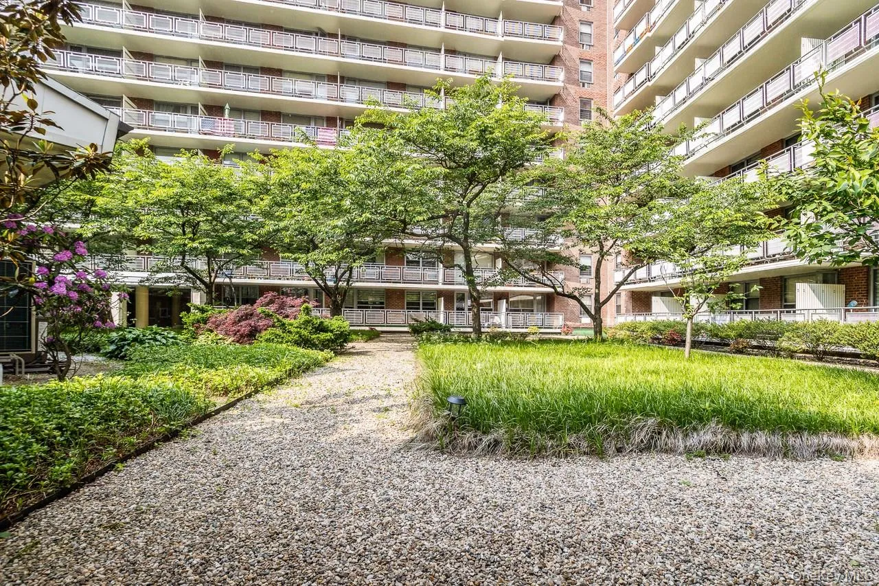Landscaped grounds featuring mature trees, shrubs, and a gravel pathway Landscaped grounds featuring mature trees, shrubs, and a gravel pathway