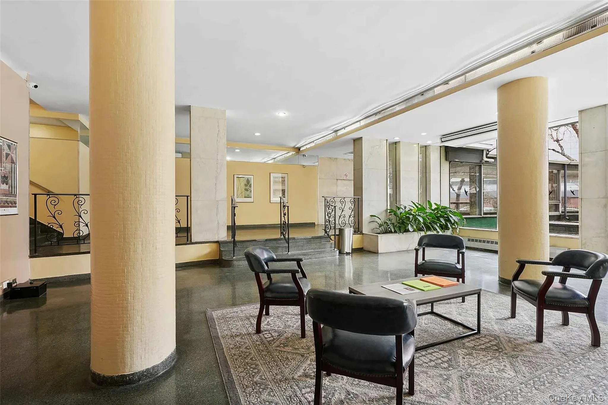 Spacious common area featuring a decorative area rug, dark flooring, and large support columns Spacious common area featuring a decorative area rug, dark flooring, and large support columns