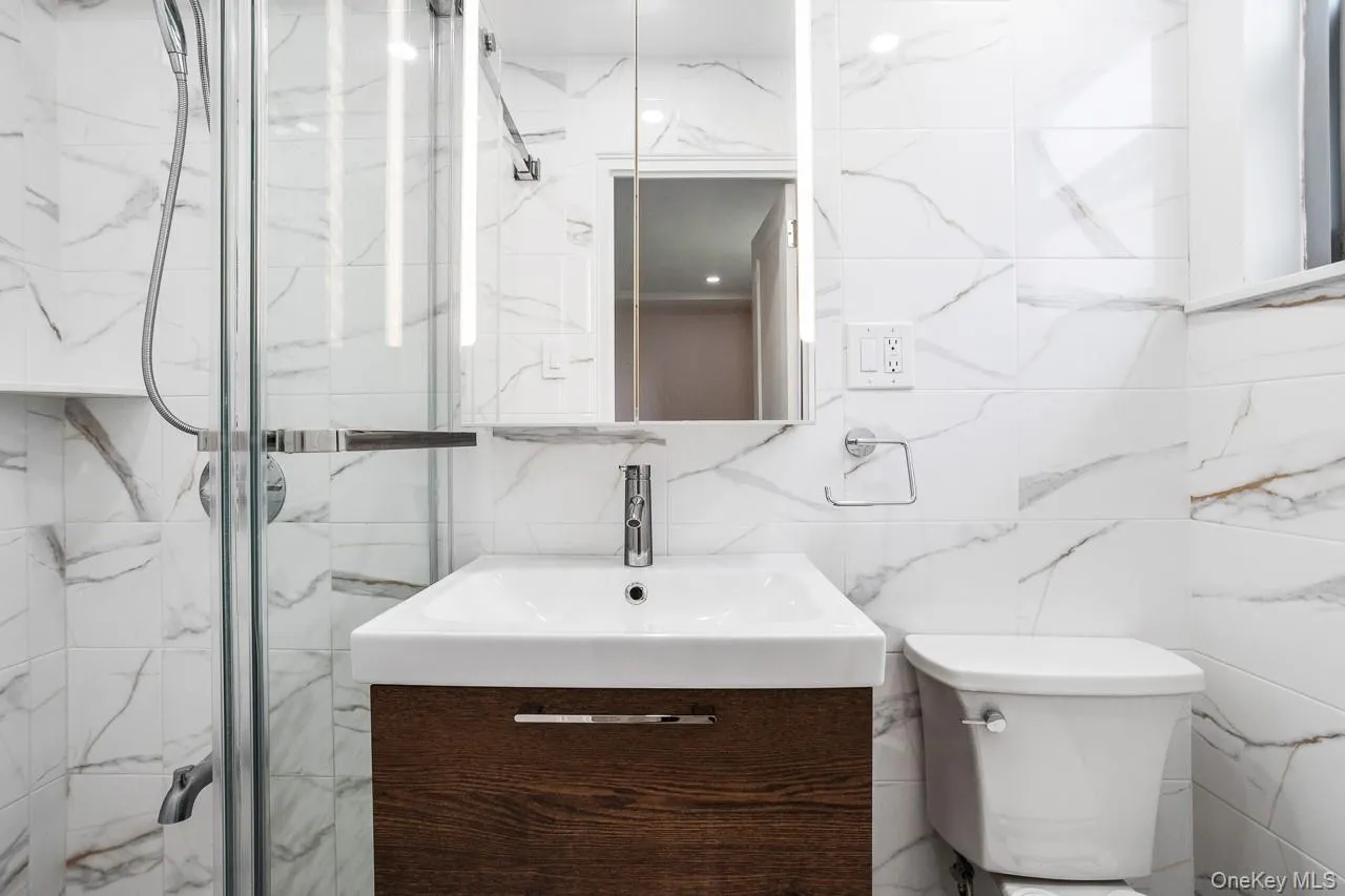 Modern bathroom featuring a floating vanity with wood-finish cabinetry, a white rectangular sink, and polished chrome fixtures Modern bathroom featuring a floating vanity with wood-finish cabinetry, a white rectangular sink, and polished chrome fixtures