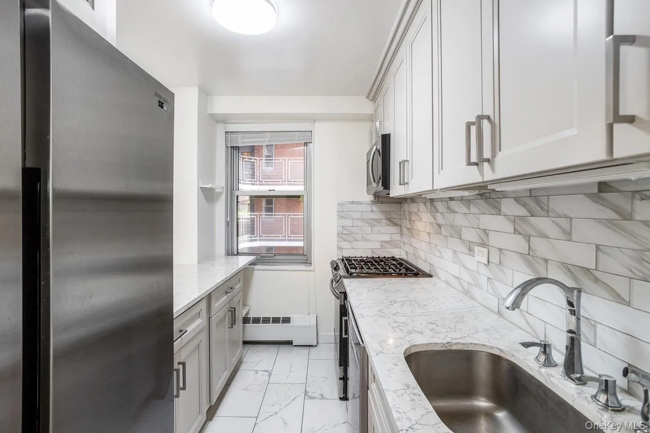 White shaker cabinetry, stainless steel appliances, white subway tile backsplash, white countertop, and white tile flooring White shaker cabinetry, stainless steel appliances, white subway tile backsplash, white countertop, and white tile flooring