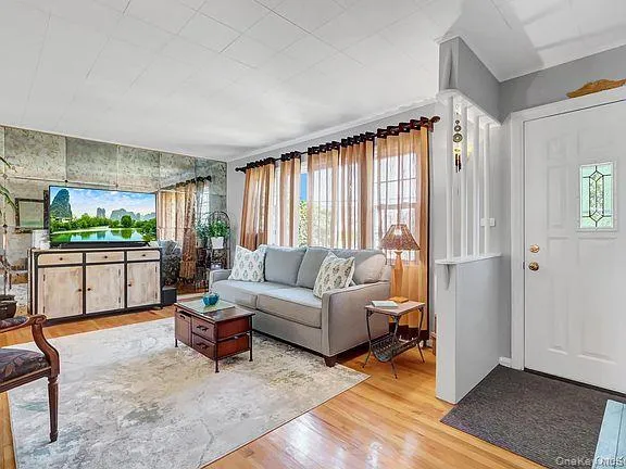 Hardwood flooring throughout, mirrored accent wall, white paneled entry door with decorative glass insert, and a partial room divider Hardwood flooring throughout, mirrored accent wall, white paneled entry door with decorative glass insert, and a partial room divider
