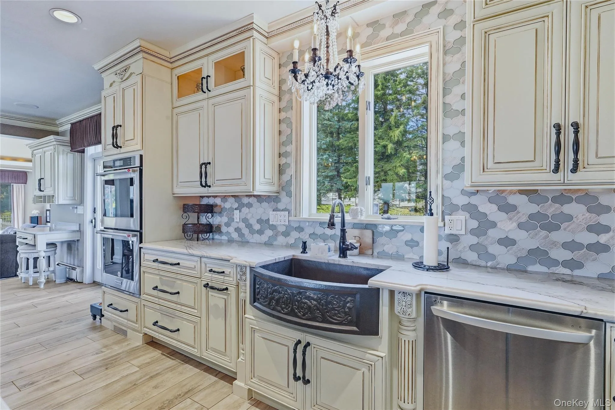 White cabinetry with dark hardware, a decorative marble backsplash, stainless steel appliances, a black farmhouse-style sink, quartzite counter tops White cabinetry with dark hardware, a decorative marble backsplash, stainless steel appliances, a black farmhouse-style sink, quartzite counter tops
