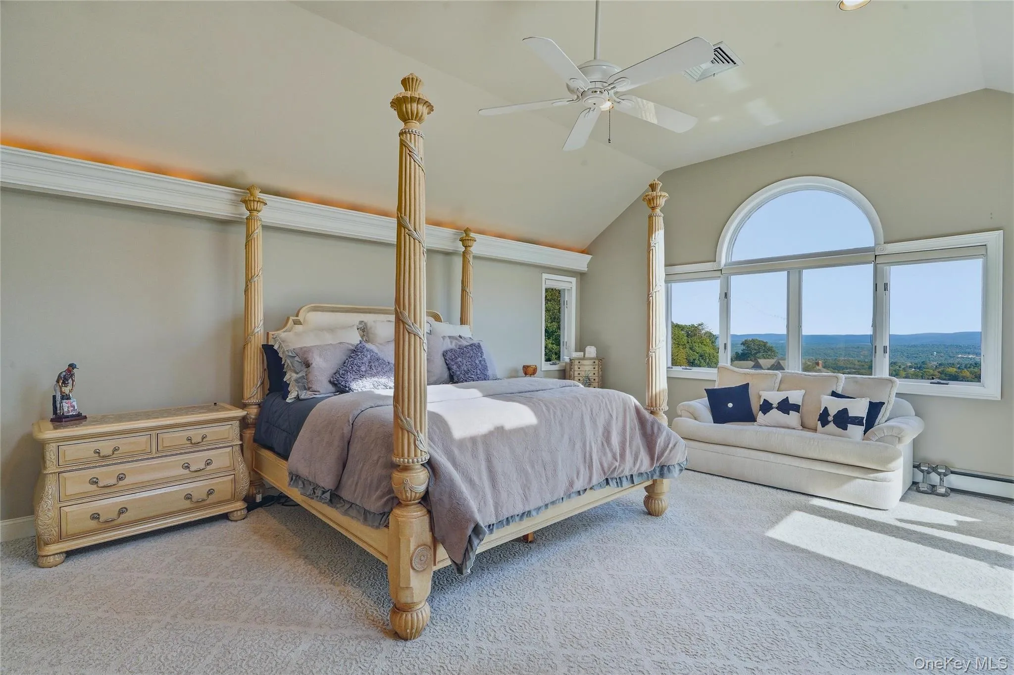 Vaulted ceiling with an overhead fan, large arched window, and plush patterned carpeting Vaulted ceiling with an overhead fan, large arched window, and plush patterned carpeting