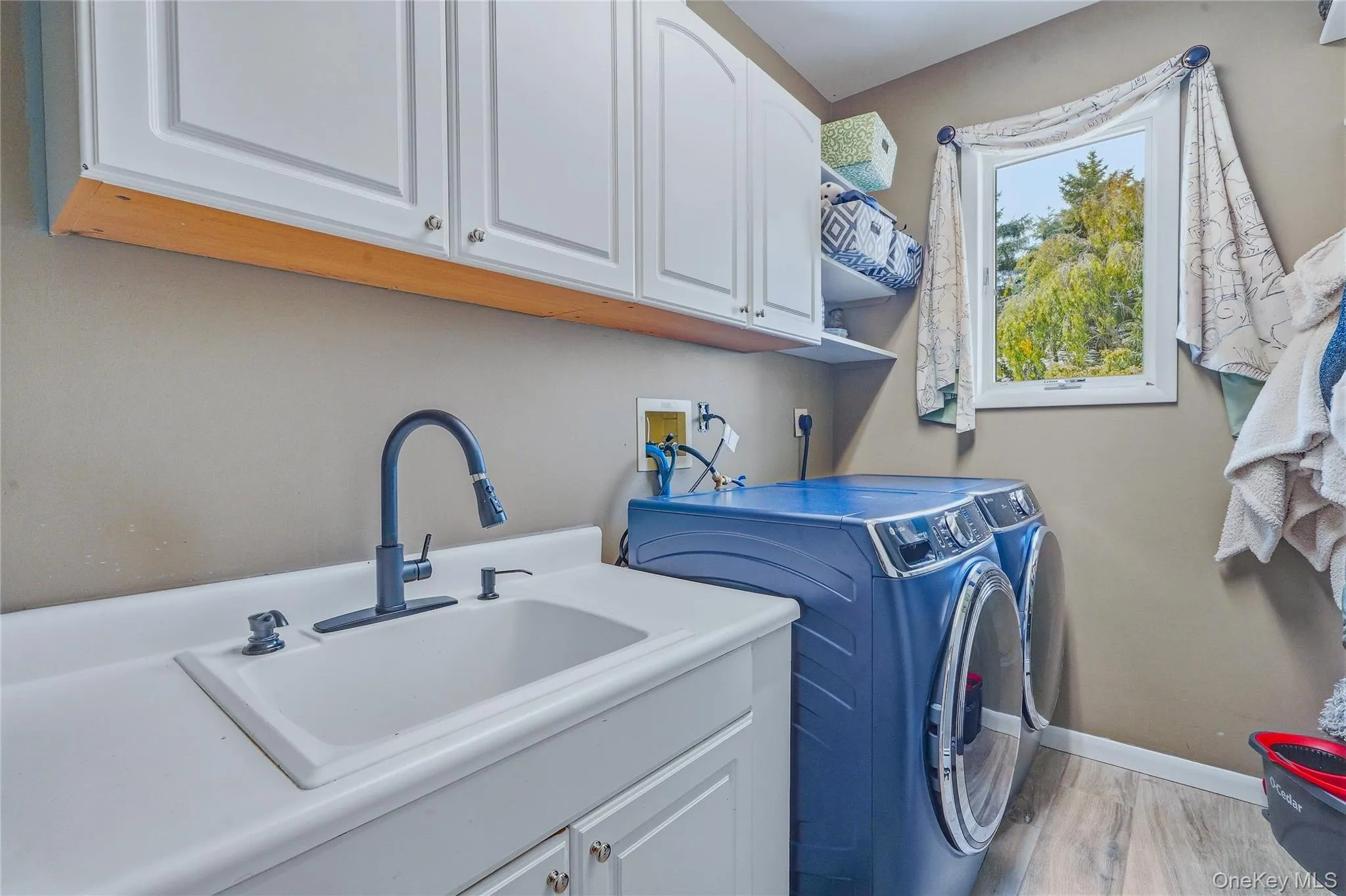 White cabinetry, a utility sink with a matte black faucet, and wood look flooring White cabinetry, a utility sink with a matte black faucet, and wood look flooring
