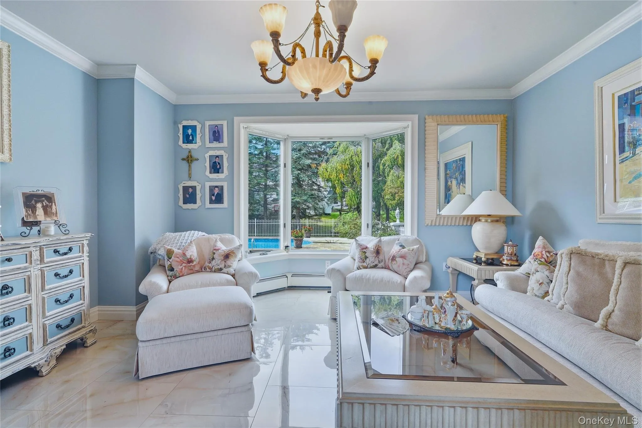 Bay window with a pool view, crown molding, chandelier, and polished tile flooring Bay window with a pool view, crown molding, chandelier, and polished tile flooring