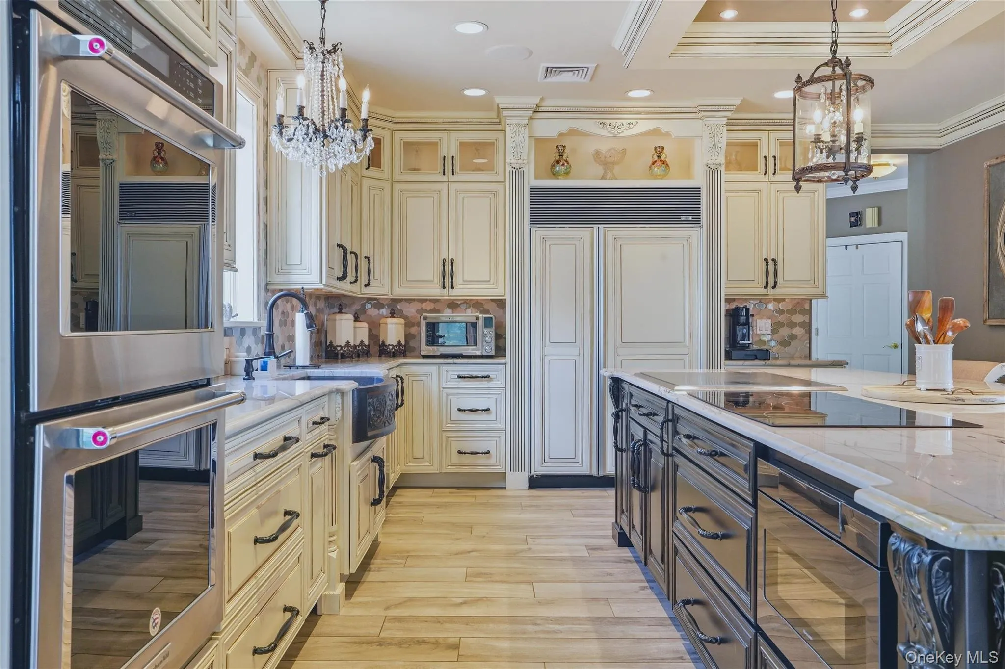 Gourmet kitchen with double wall ovens, integrated refrigerator, custom cabinetry, large kitchen island with cooktop, quartzite counter tops, and wood-look flooring Gourmet kitchen with double wall ovens, integrated refrigerator, custom cabinetry, large kitchen island with cooktop, quartzite counter tops, and wood-look flooring