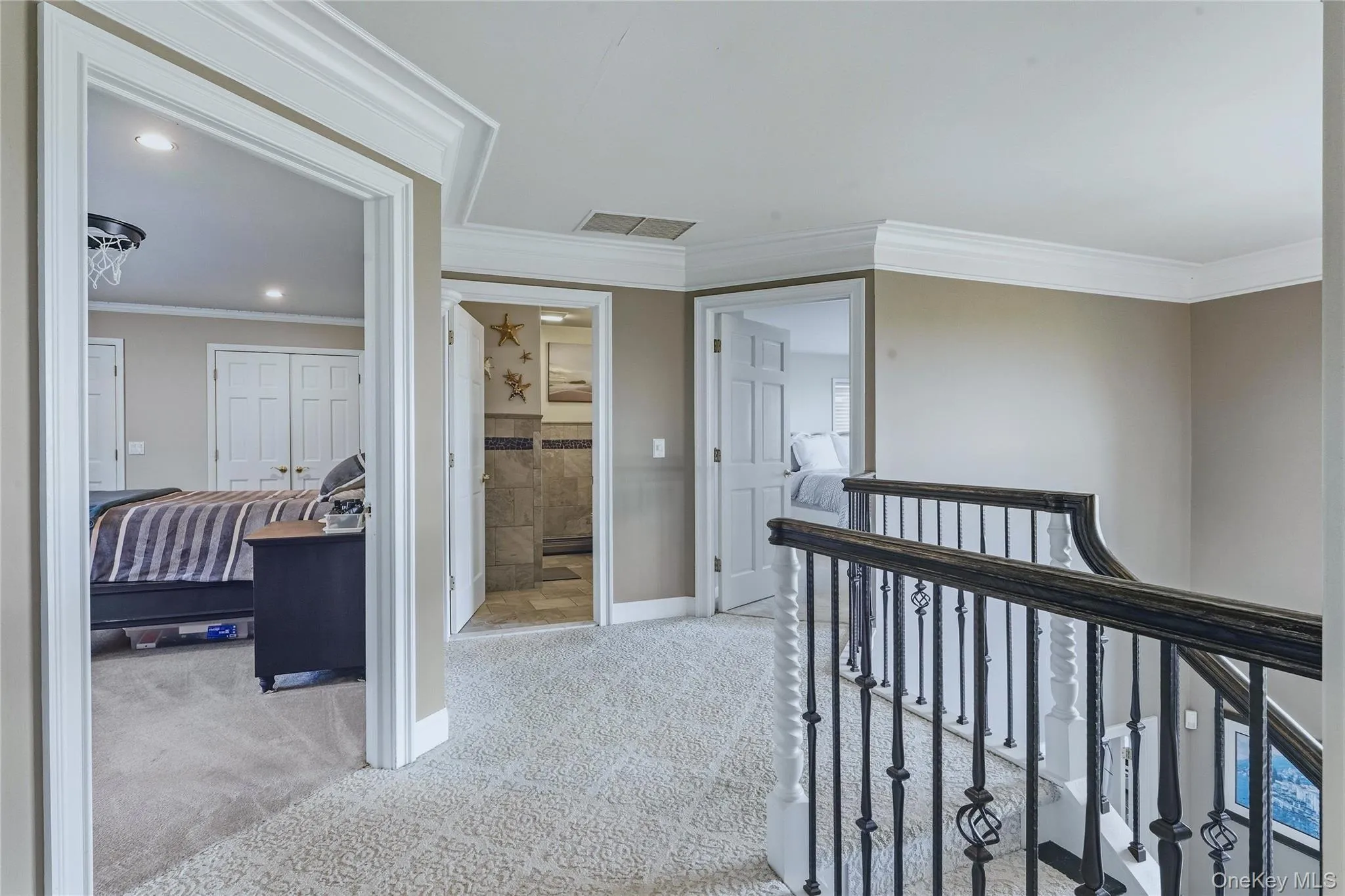 Upper-level hallway with carpeted flooring, crown molding, recessed lighting, and a wrought iron banister Upper-level hallway with carpeted flooring, crown molding, recessed lighting, and a wrought iron banister