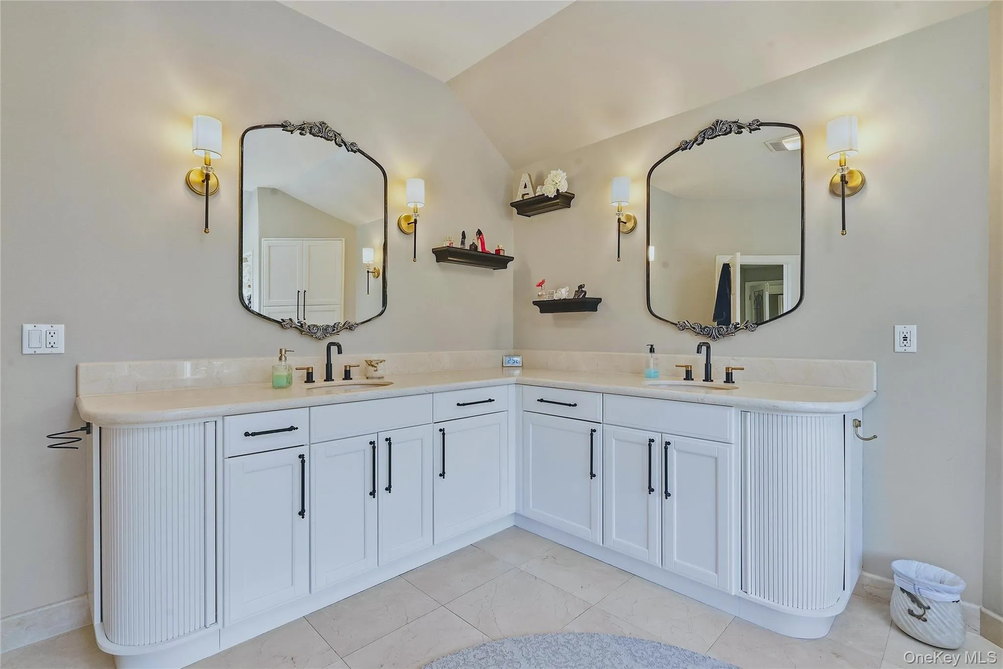 Dual vanity with white cabinetry and black hardware, marble flooring Dual vanity with white cabinetry and black hardware, marble flooring