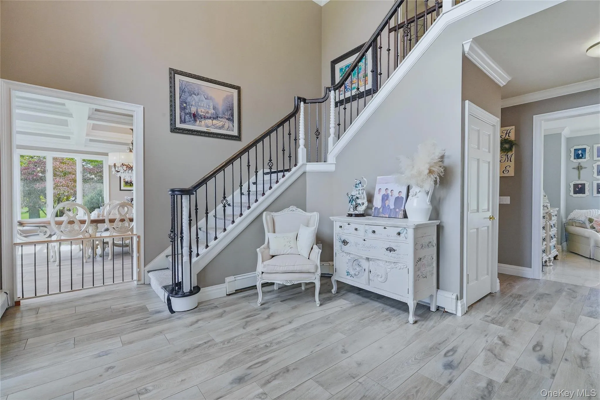 Two-story foyer with wood-look flooring, wrought iron staircase, crown molding, and an arched doorway Two-story foyer with wood-look flooring, wrought iron staircase, crown molding, and an arched doorway