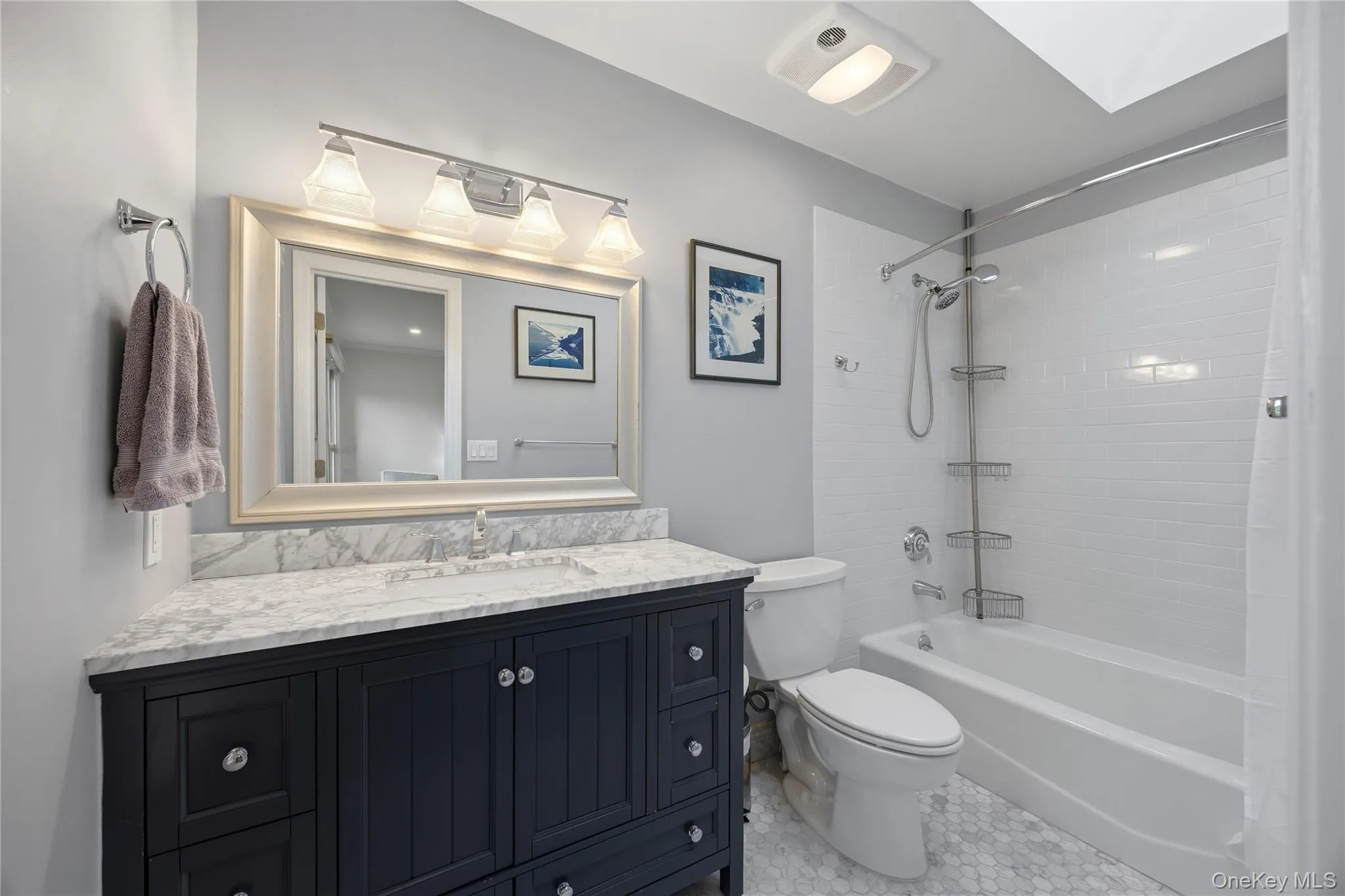 Updated Primary Bathroom (2020) with marble vanity & floor, bathtub and skylight Updated Primary Bathroom (2020) with marble vanity & floor, bathtub and skylight