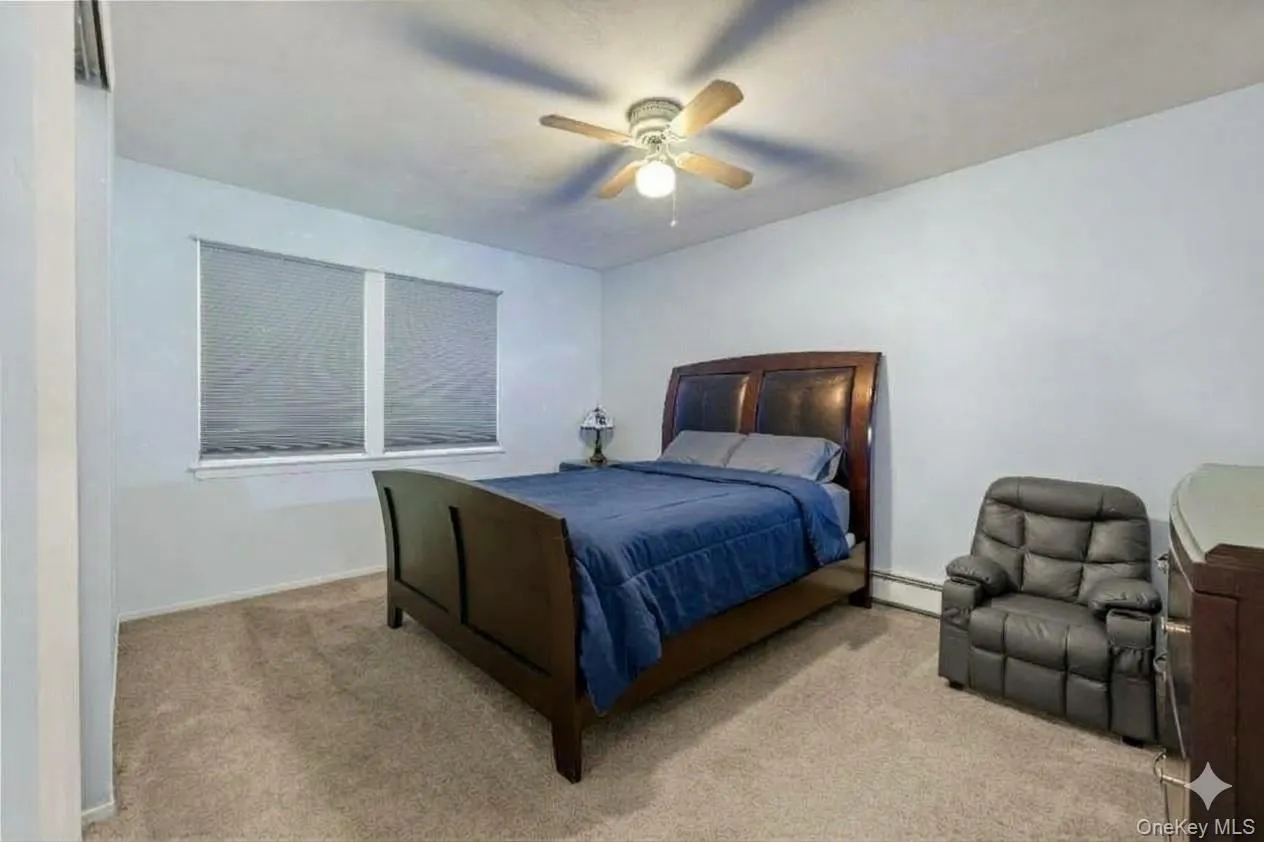 Recessed window with privacy blinds, ceiling fan with integrated lighting, and carpeted flooring. AI edited. Recessed window with privacy blinds, ceiling fan with integrated lighting, and carpeted flooring. AI edited.