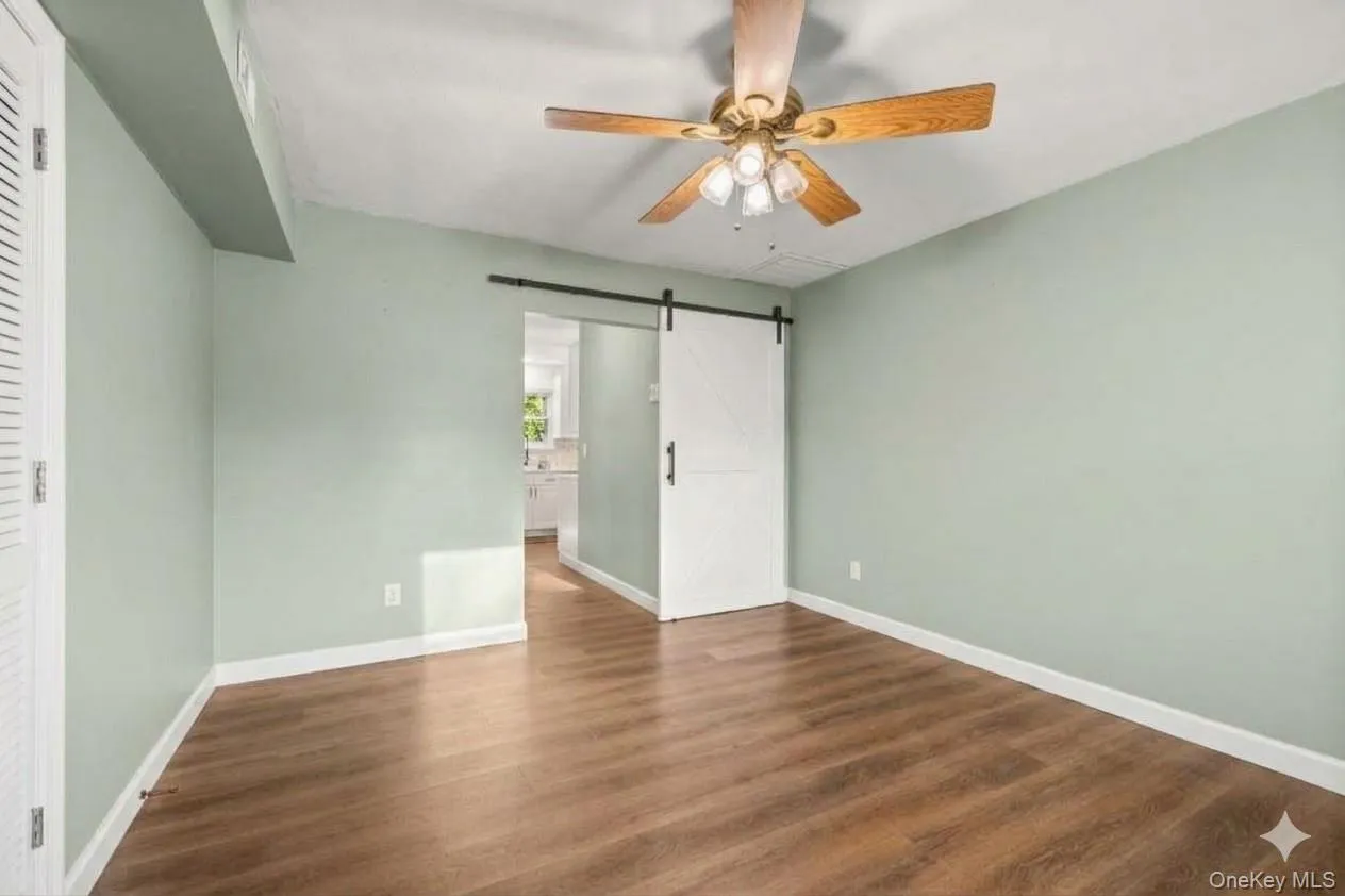 Bonus room on main level. Wood-finish flooring, ceiling fan with light fixture, sliding barn door. AI edited, all furniture removed. Bonus room on main level. Wood-finish flooring, ceiling fan with light fixture, sliding barn door. AI edited, all furniture removed.