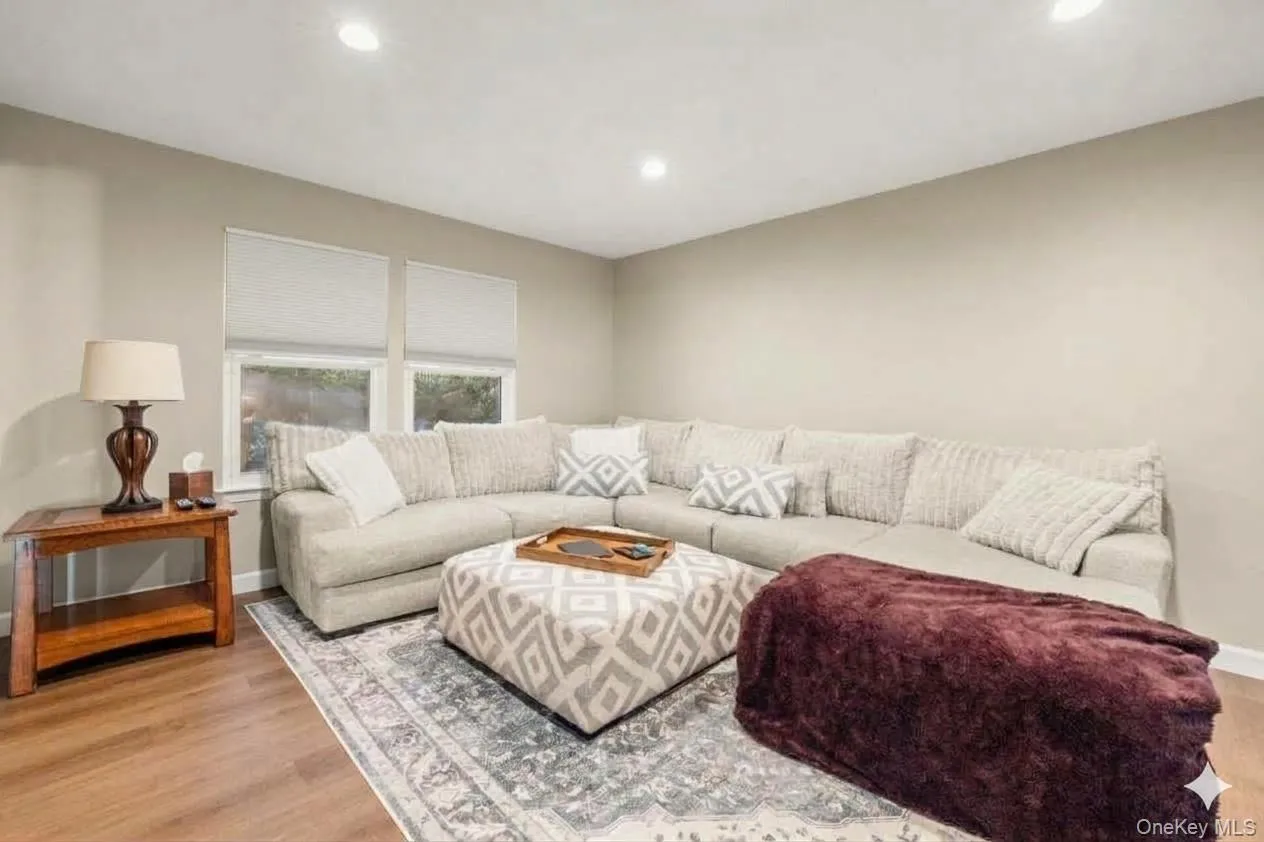 SPACIOUS Living Room. Recessed lighting, wood-finish flooring, two windows with roller shades, and light-toned walls., AI edited. SPACIOUS Living Room. Recessed lighting, wood-finish flooring, two windows with roller shades, and light-toned walls., AI edited.