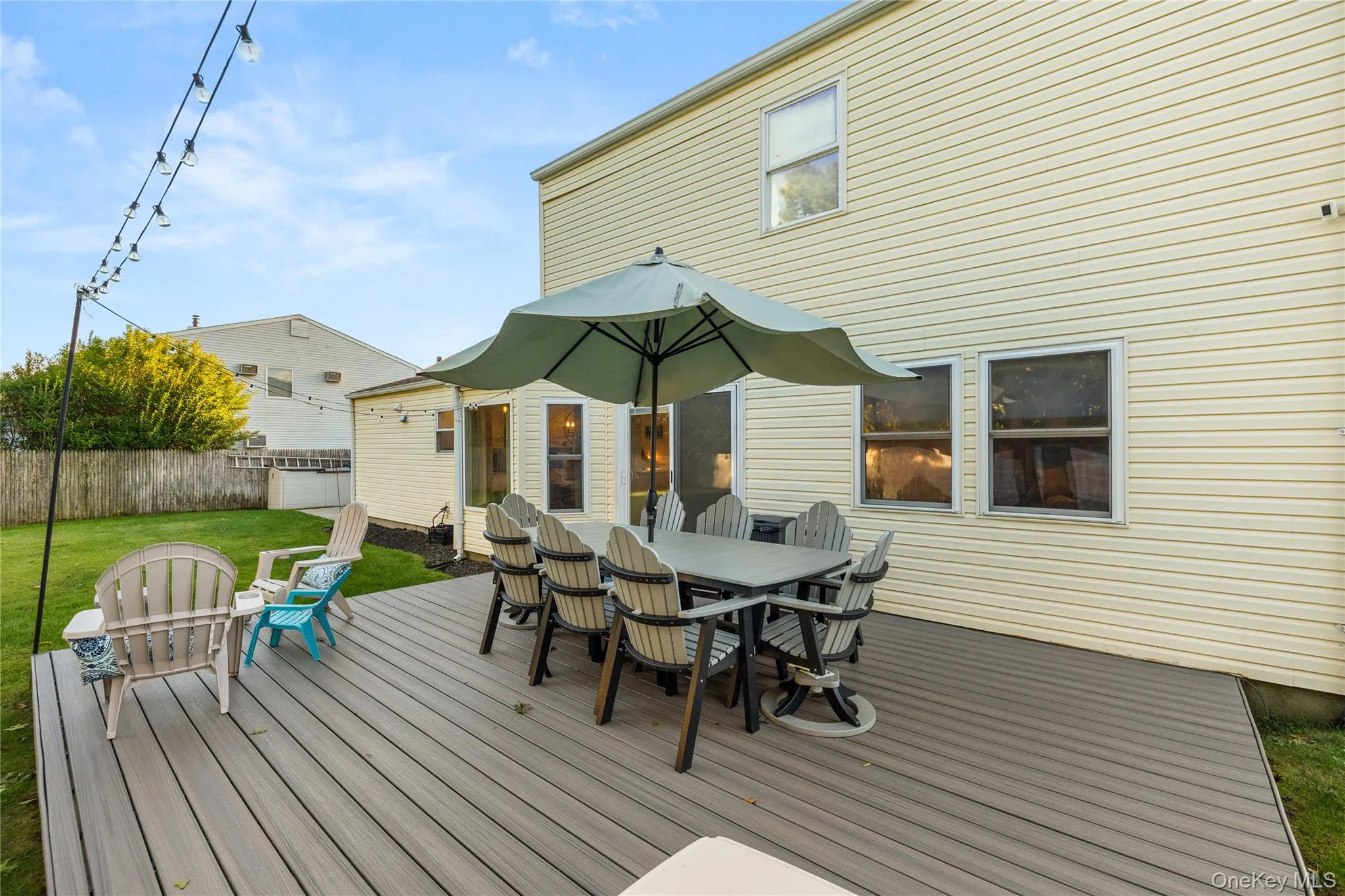 Expansive Trex deck featuring integrated dining and lounge areas, anchored by a center umbrella for shade Expansive Trex deck featuring integrated dining and lounge areas, anchored by a center umbrella for shade