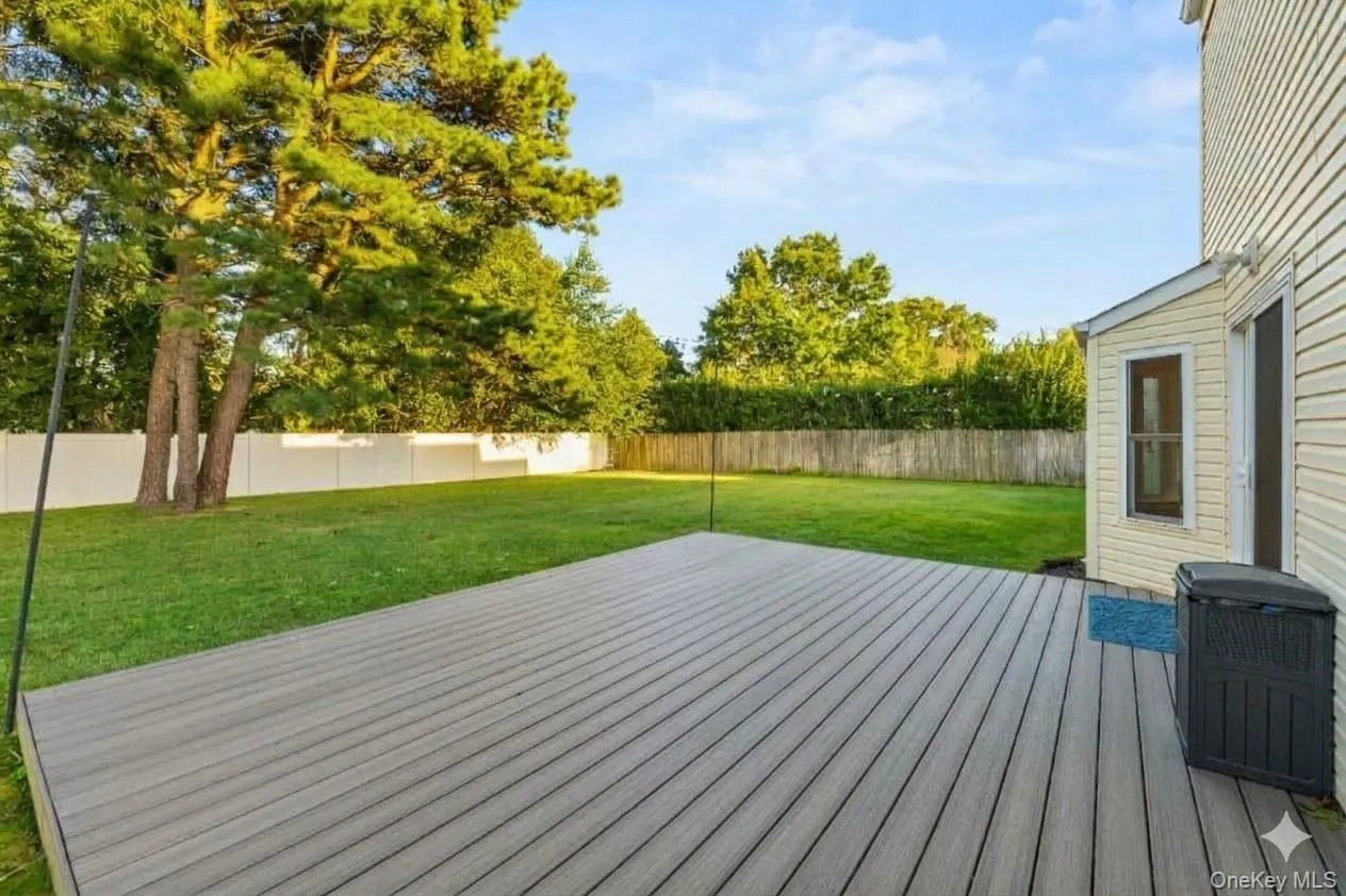 Expansive backyard featuring Trex decking, manicured lawn, mature trees, and privacy fencing. AI edited, removed all furniture. Expansive backyard featuring Trex decking, manicured lawn, mature trees, and privacy fencing. AI edited, removed all furniture.