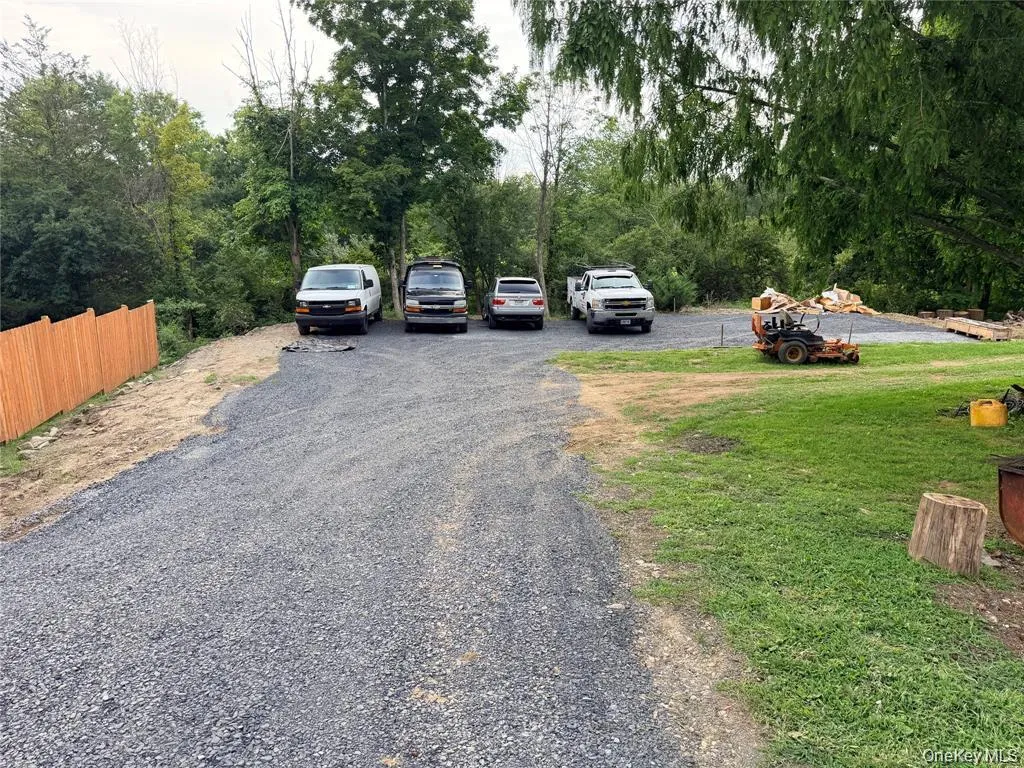 Expansive gravel driveway with a newly installed wood fence and a lush grassy area Expansive gravel driveway with a newly installed wood fence and a lush grassy area