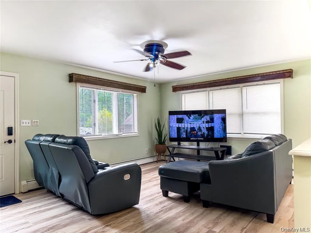 Wood-finish flooring, ceiling fan, and large windows with blinds Wood-finish flooring, ceiling fan, and large windows with blinds