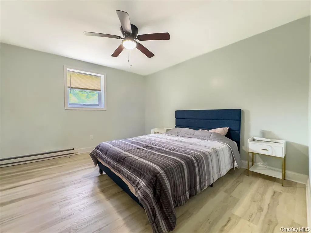 Wood-finish flooring, single window with roller shade, and ceiling fan with light fixture Wood-finish flooring, single window with roller shade, and ceiling fan with light fixture