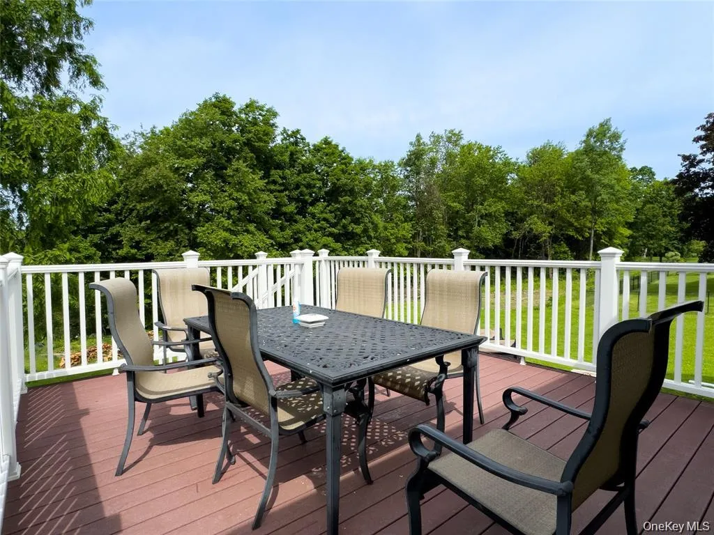 Expansive outdoor deck featuring wood-finish flooring and white railings Expansive outdoor deck featuring wood-finish flooring and white railings