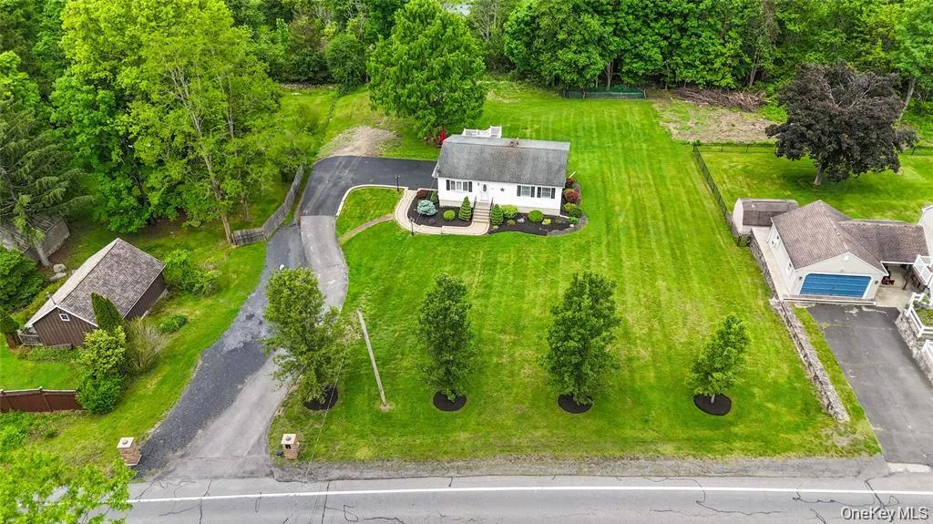 White exterior residence with a gray shingle roof, dark shutters, and a well-maintained front lawn White exterior residence with a gray shingle roof, dark shutters, and a well-maintained front lawn