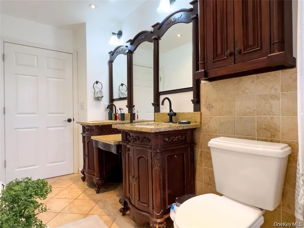 Dual vanity with ornate wood cabinetry, granite countertops, and black fixtures Dual vanity with ornate wood cabinetry, granite countertops, and black fixtures