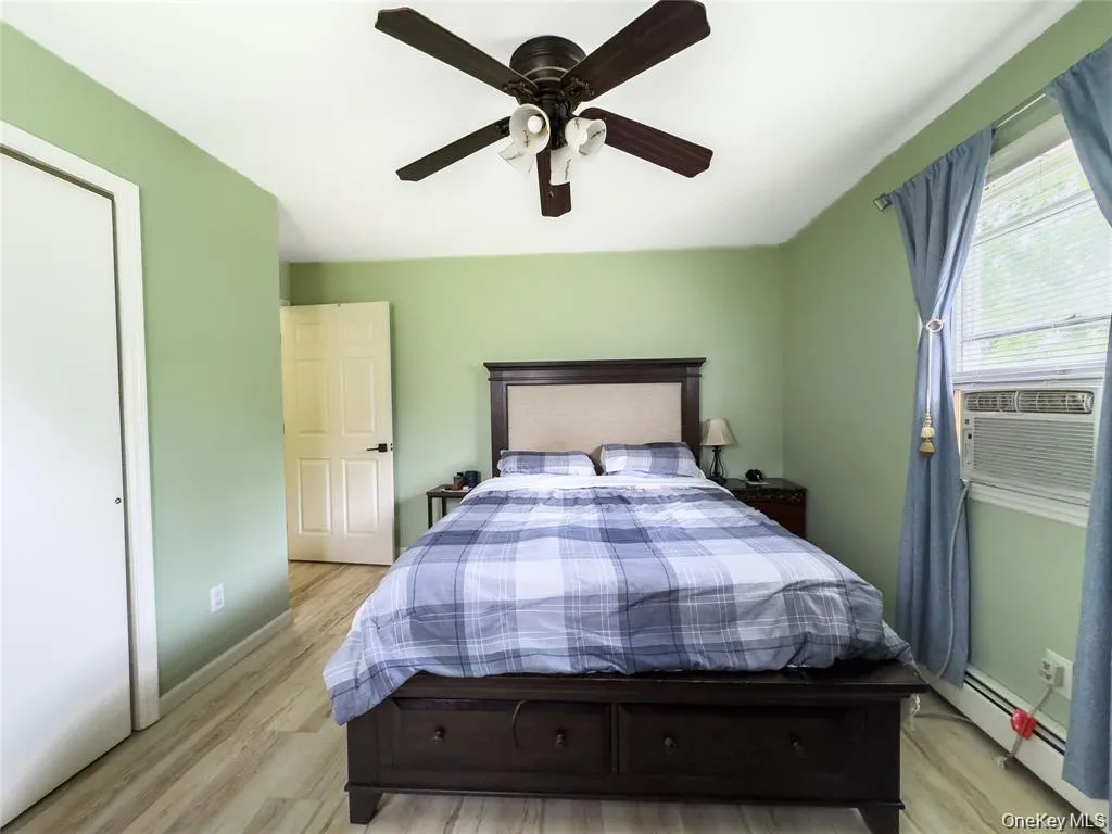 Ceiling fan with integrated lighting, wood-finish flooring, and window-mounted air conditioning unit Ceiling fan with integrated lighting, wood-finish flooring, and window-mounted air conditioning unit