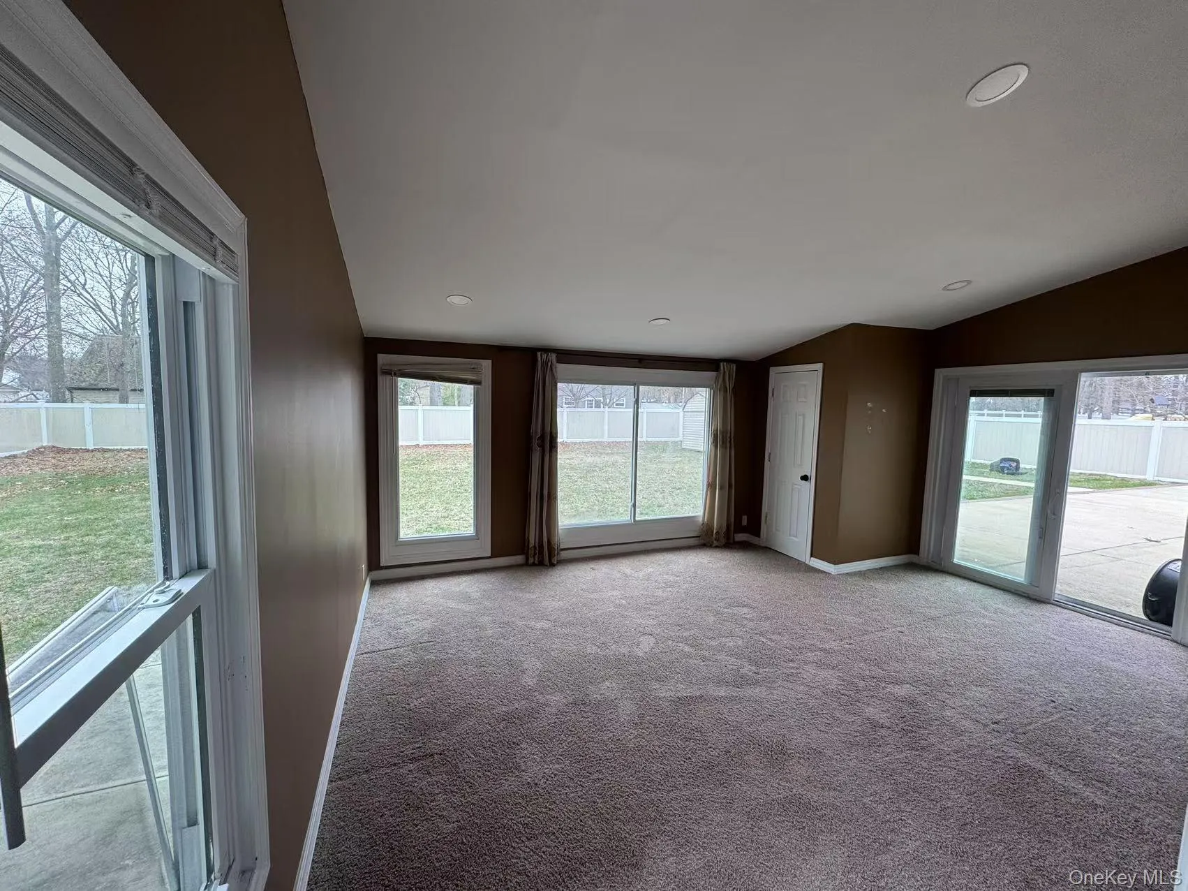 Carpeted spare room featuring baseboards and lofted ceiling Carpeted spare room featuring baseboards and lofted ceiling