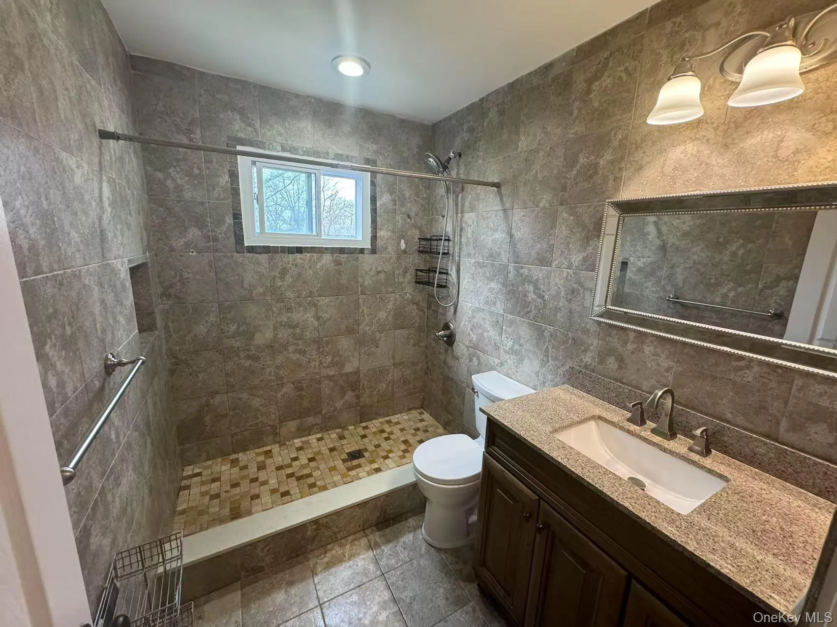 Full bath featuring vanity, tasteful backsplash, tile walls, a tile shower, and toilet Full bath featuring vanity, tasteful backsplash, tile walls, a tile shower, and toilet