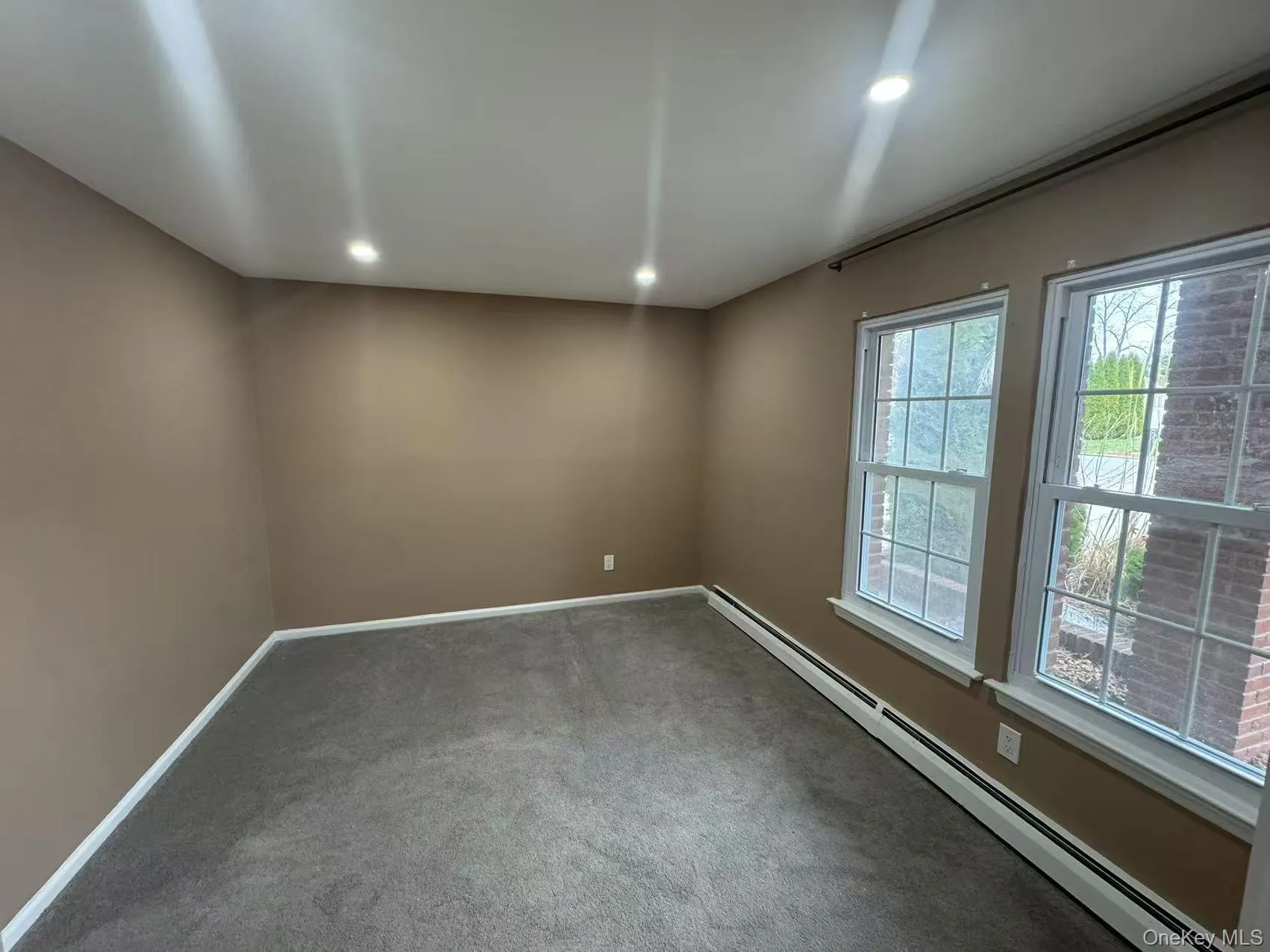 Carpeted spare room with baseboards, recessed lighting, and a baseboard radiator Carpeted spare room with baseboards, recessed lighting, and a baseboard radiator