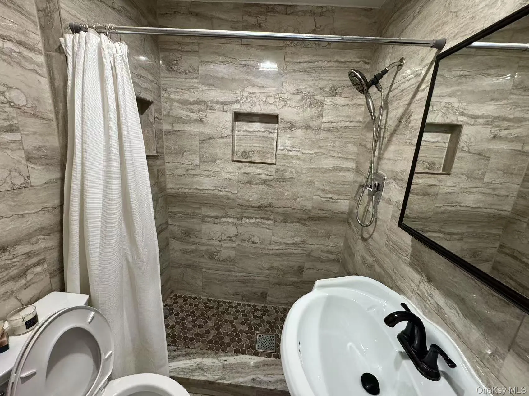 Bathroom featuring a sink, a stall shower, and toilet Bathroom featuring a sink, a stall shower, and toilet